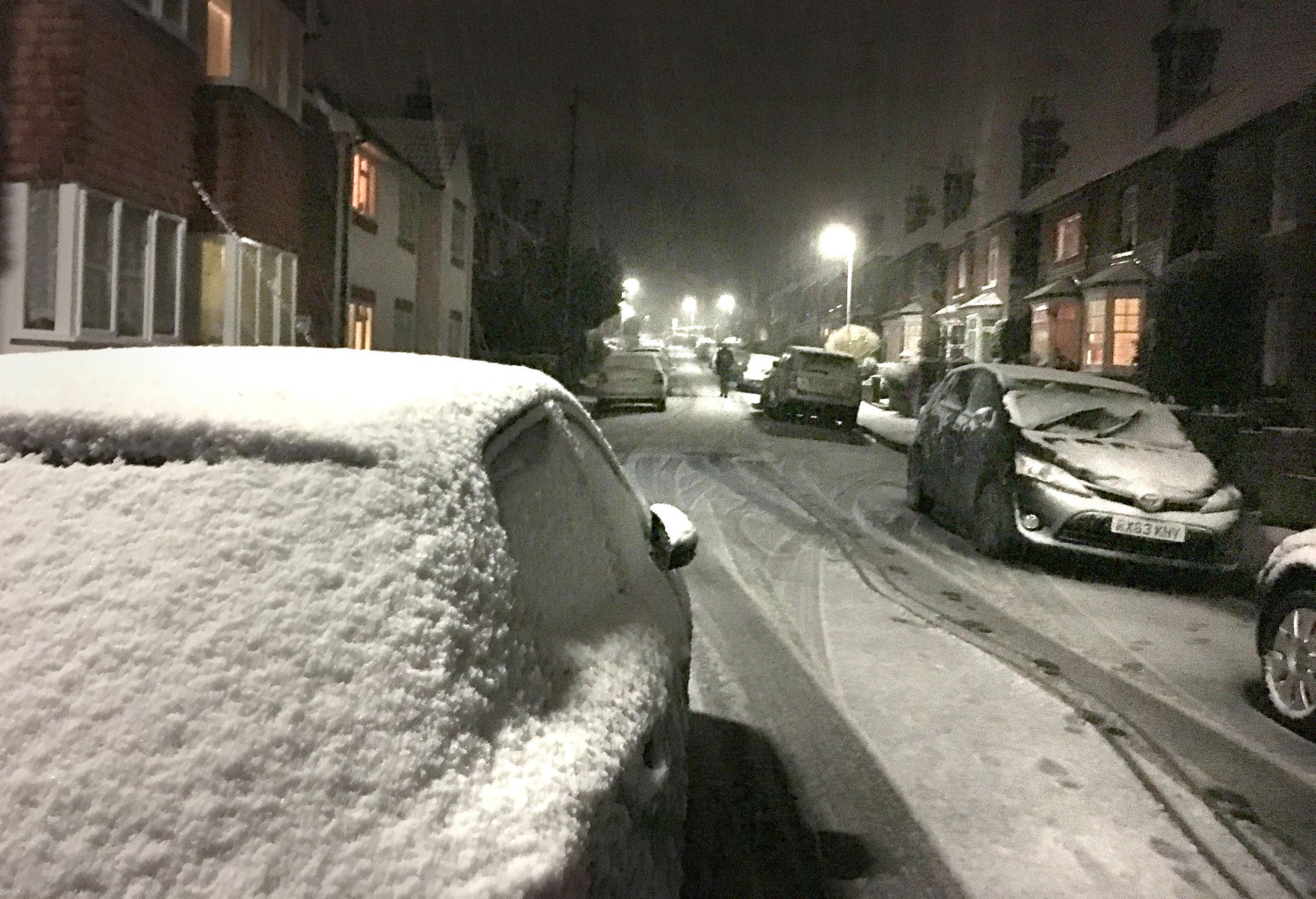 Roads, including this one in Godalming, Surrey, were blanketed with snow as night fell on Thursday