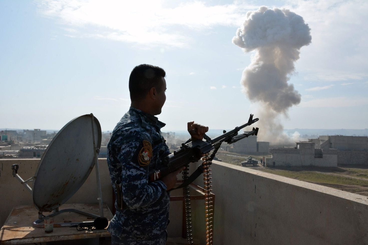 An Iraqi soldier watches the smoke billow from a booby-trapped car left behind by Isis in Mosul