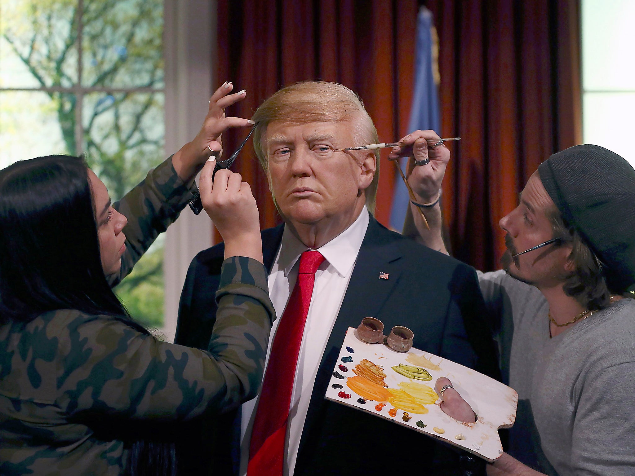 Gallery assistants pose, pretending to put the finishing touches to the hair and make-up of a waxwork of US President-elect Donald Trump, during a media event at Madame Tussauds in London