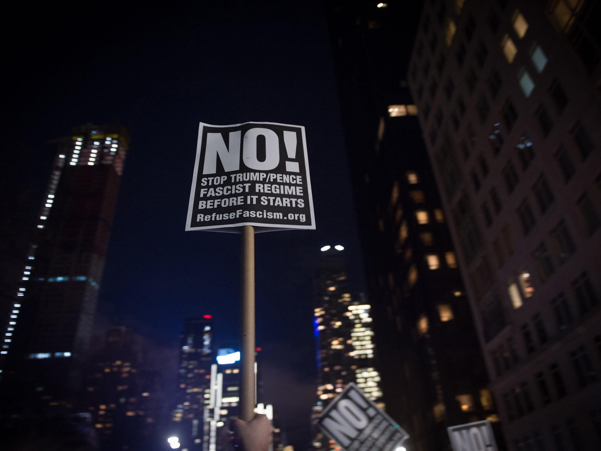 An activist holds up a sign at the "We Stand United" rally on the eve of US President-elect Donald Trump's inauguration outside Trump International Hotel and Tower in New York on January 19, 2017 in New York