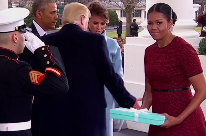 Ms Obama looks around for somewhere to put the ribbon-wrapped box, before shooting a swift look of desperation at the camera