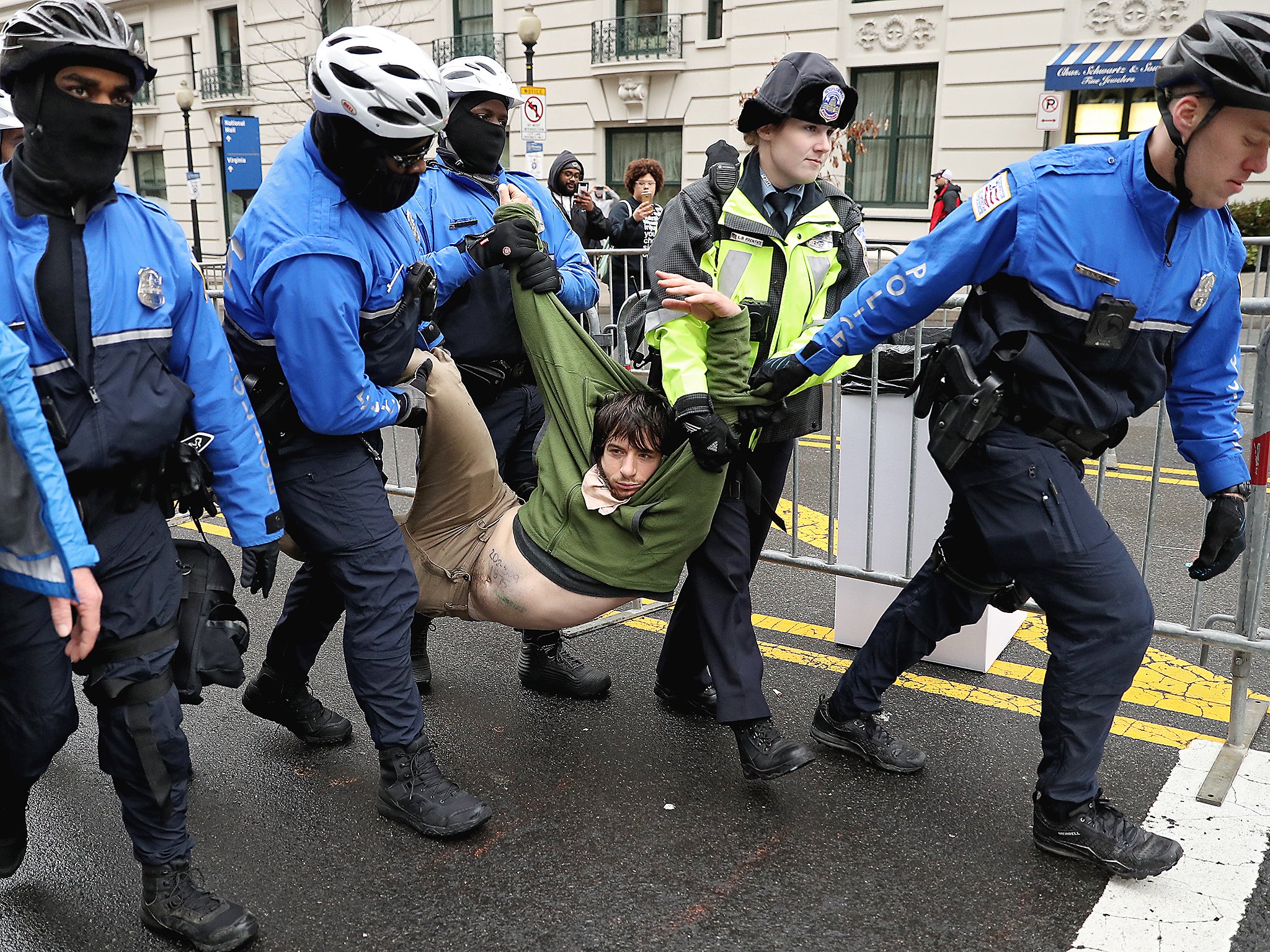 A protester is dragged away from a public access point to the National Mall on 14th Street NW prior to the inauguration in Washington DC