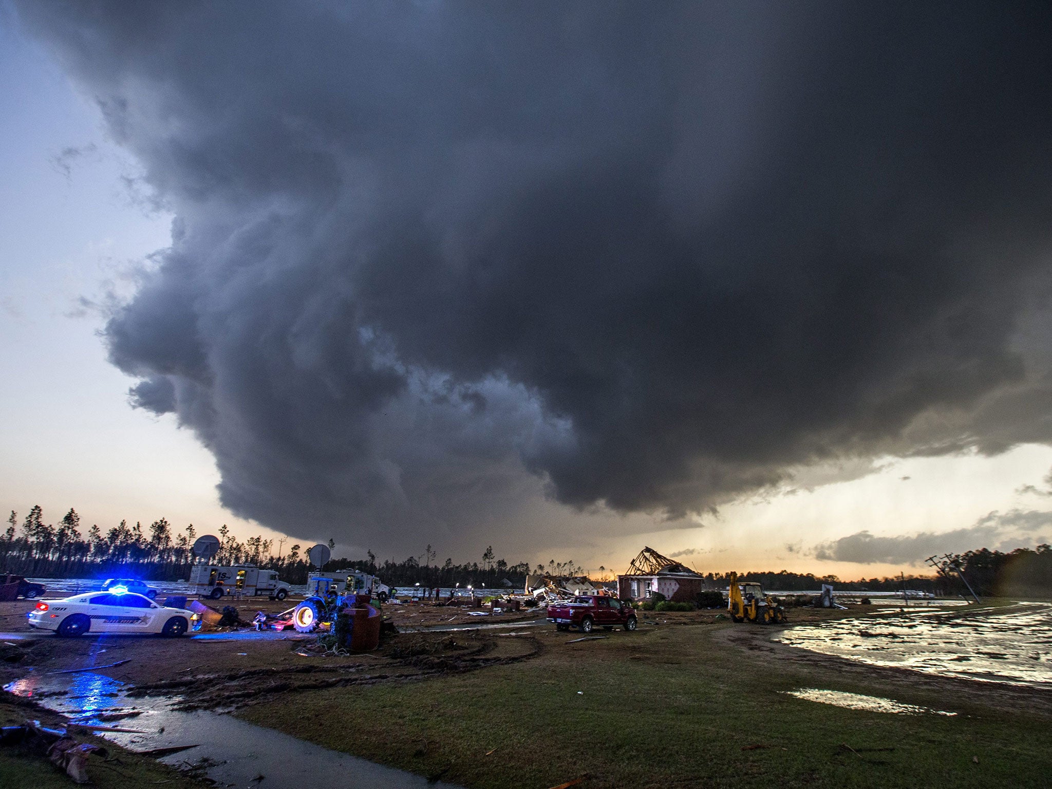 Storm clouds approach emergency crews at the scene of a house cut in half by a tornado near where seven people were killed outside Adel, Georgia USA on 22 January 2017