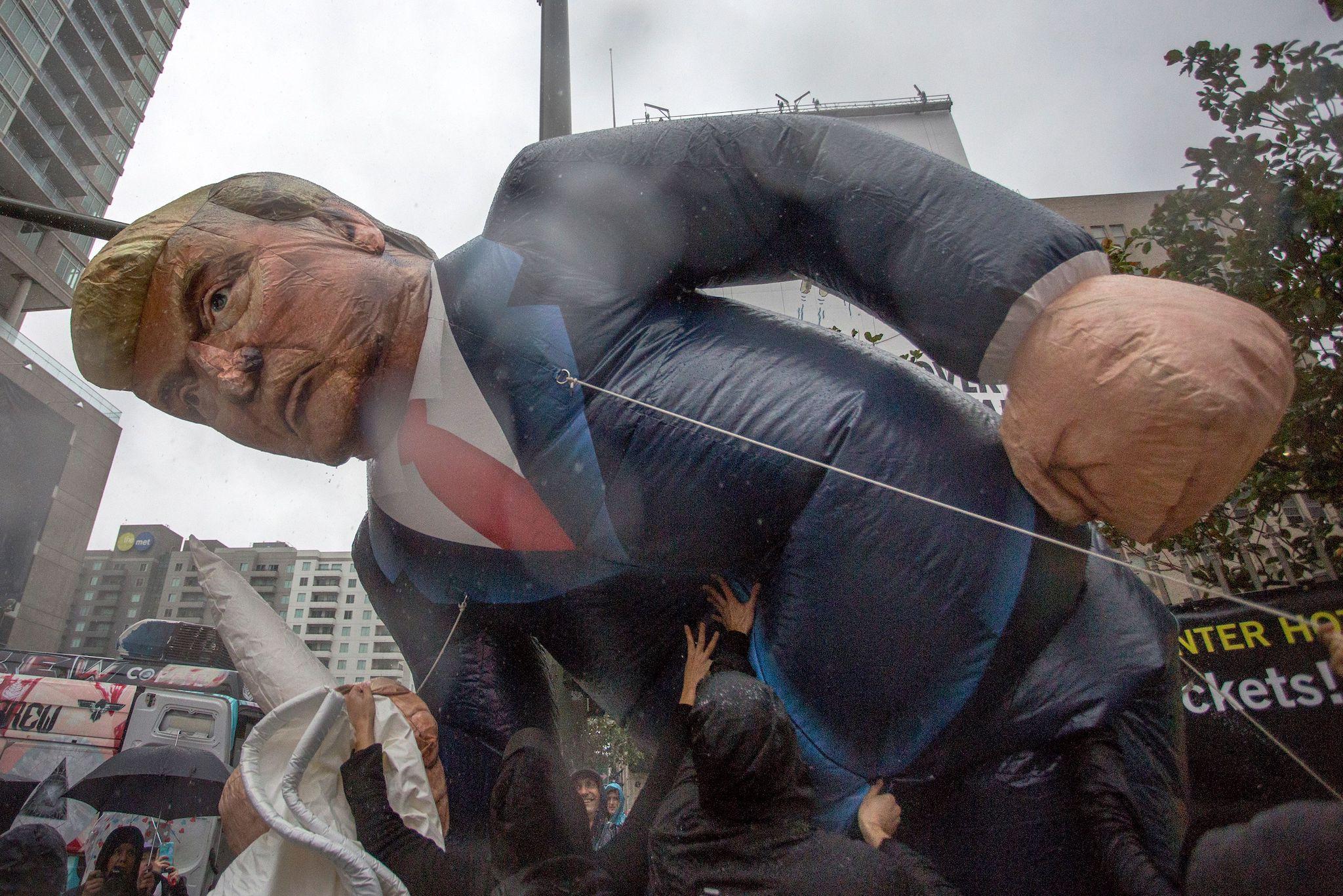 People inflate a likeness of Donald Trump as they march in the rain to protest his inauguration on January 20, 2017 in Los Angeles, California (DAVID MCNEW/AFP/Getty Images)