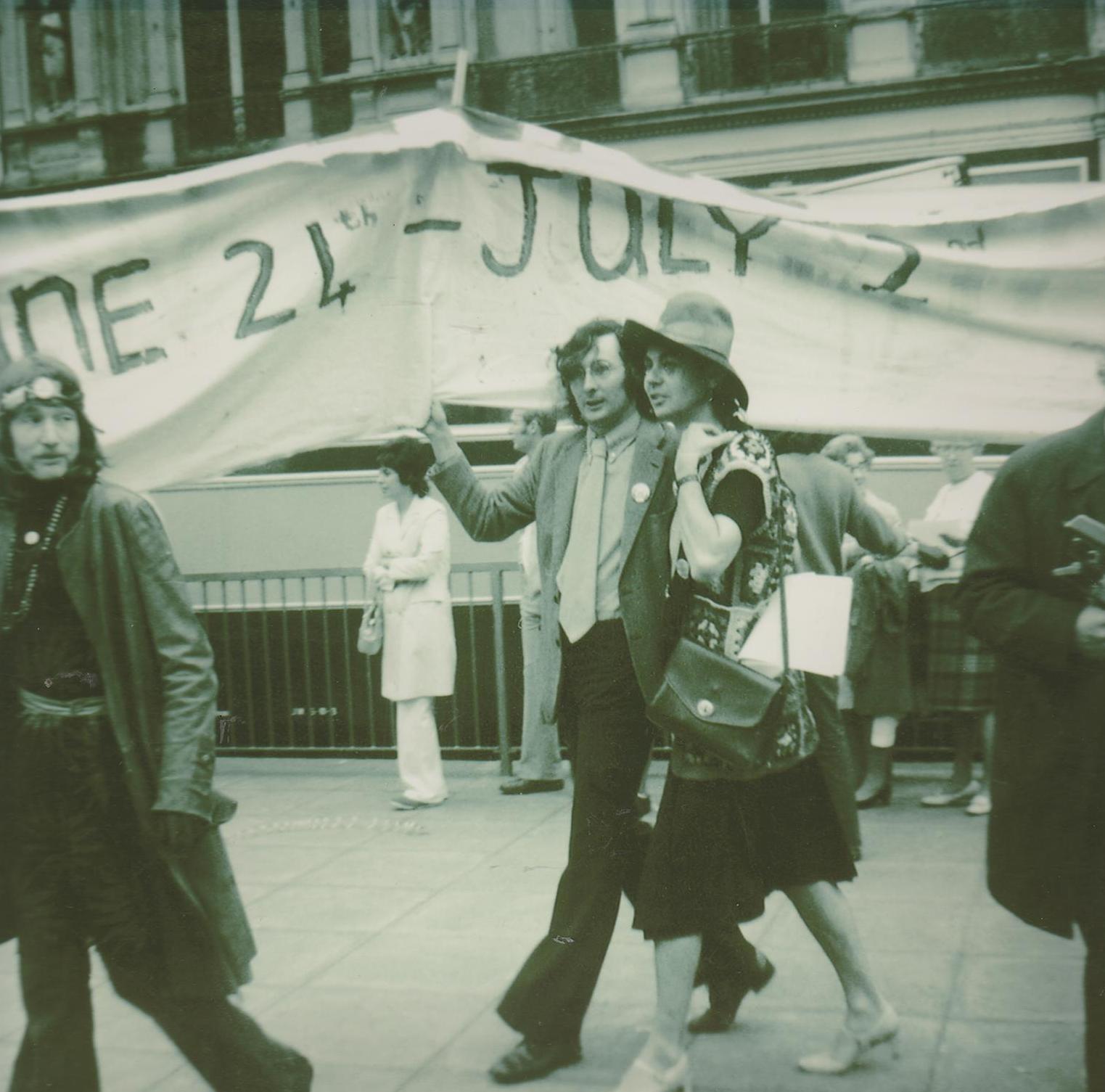 Lumsden linking arms with Michael James, a GLF Radical Queen protestor, dressed in drag, in 1971.