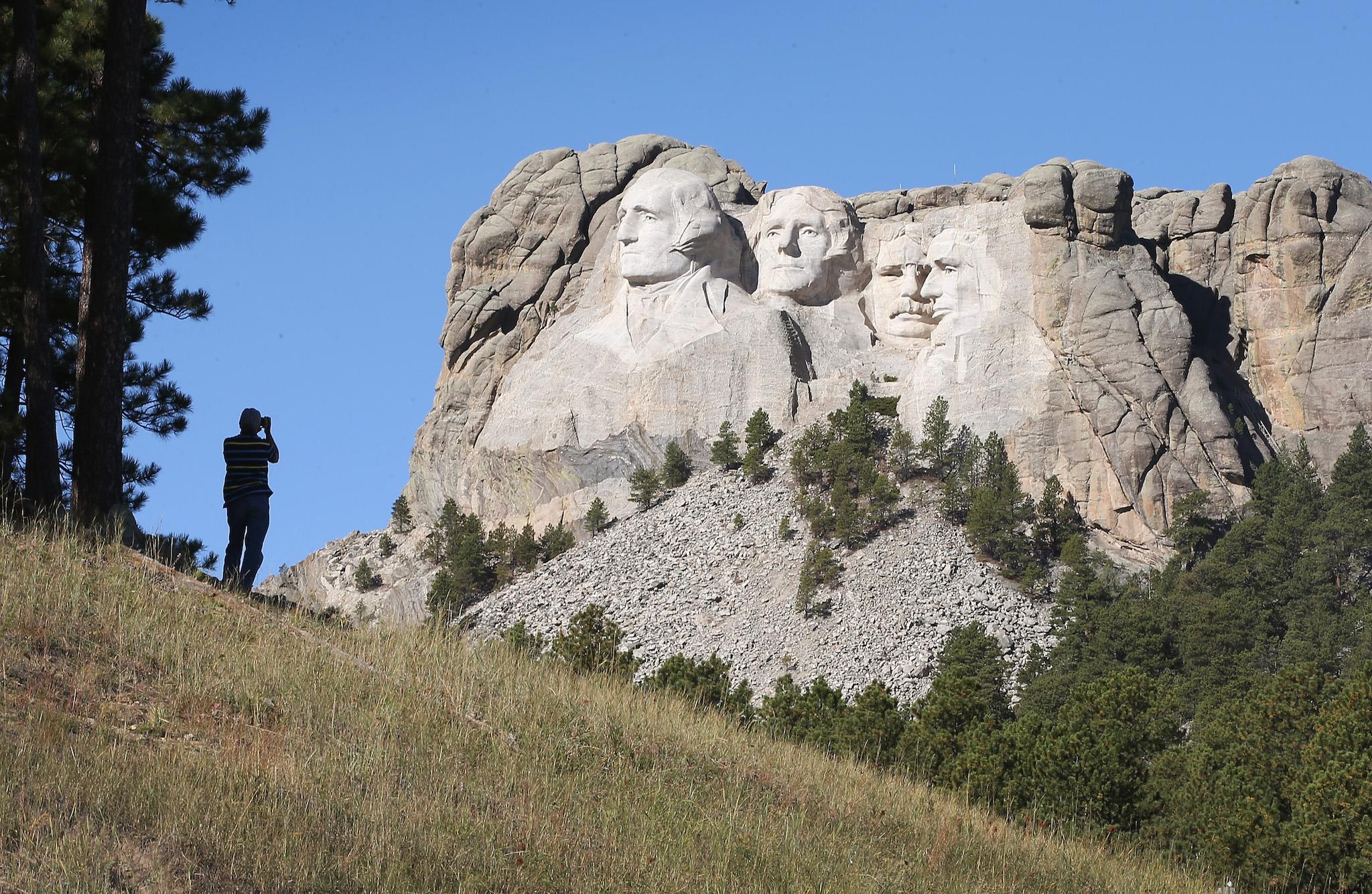 A tourist takes a picture of Mount Rushmore National Memorial from outside the park on October 1, 2013 in Keystone, South Dakota