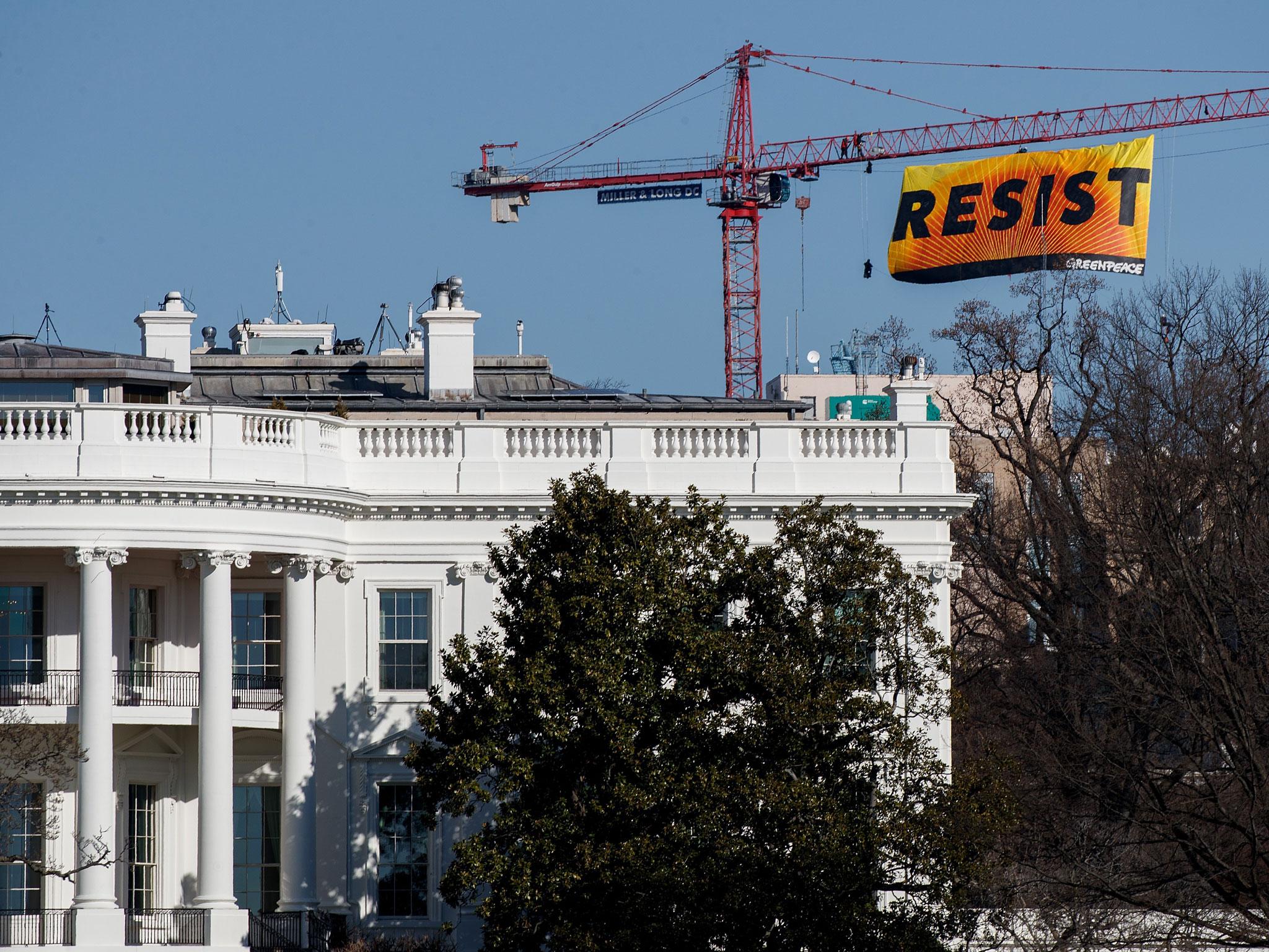 Protesters unfurl a banner atop a crane at the construction site of the former Washington Post office building