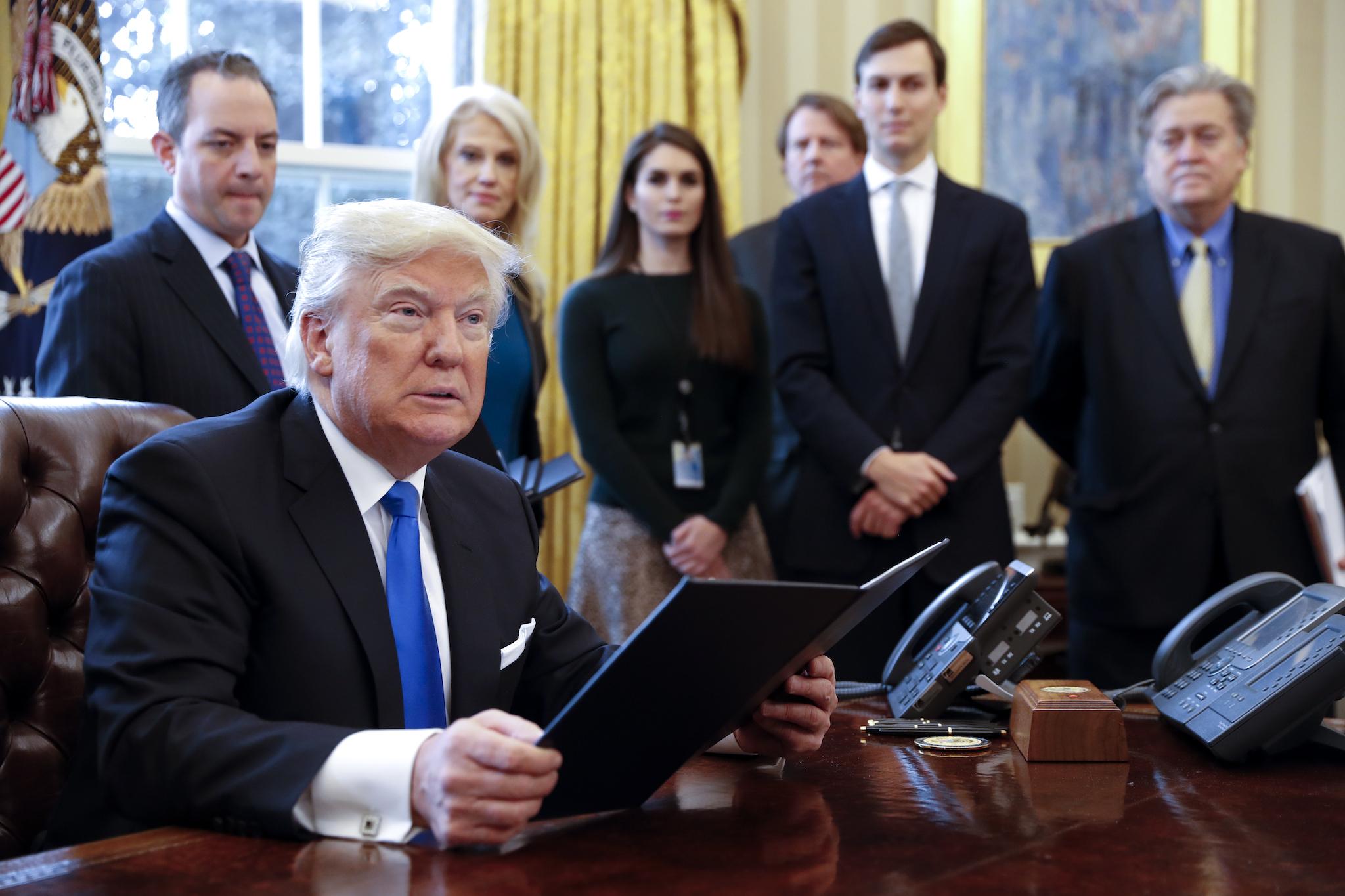 President Donald Trump signs one of five executive orders related to the oil pipeline industry in the Oval Office of the White House, 24 January, 2017 in Washington, DC