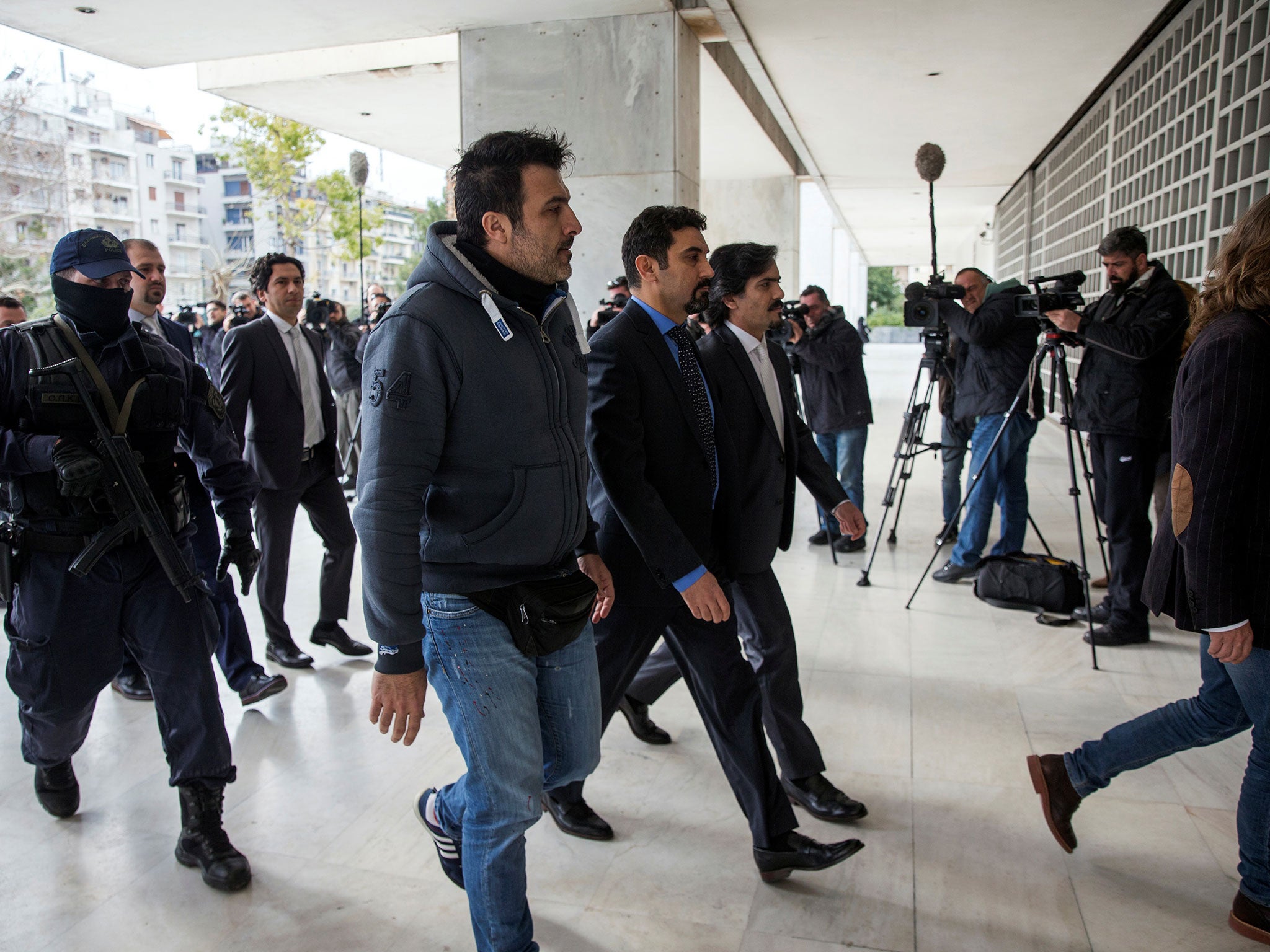 The eight Turkish soldiers are escorted by police officers as they arrive at the Supreme Court in Athens