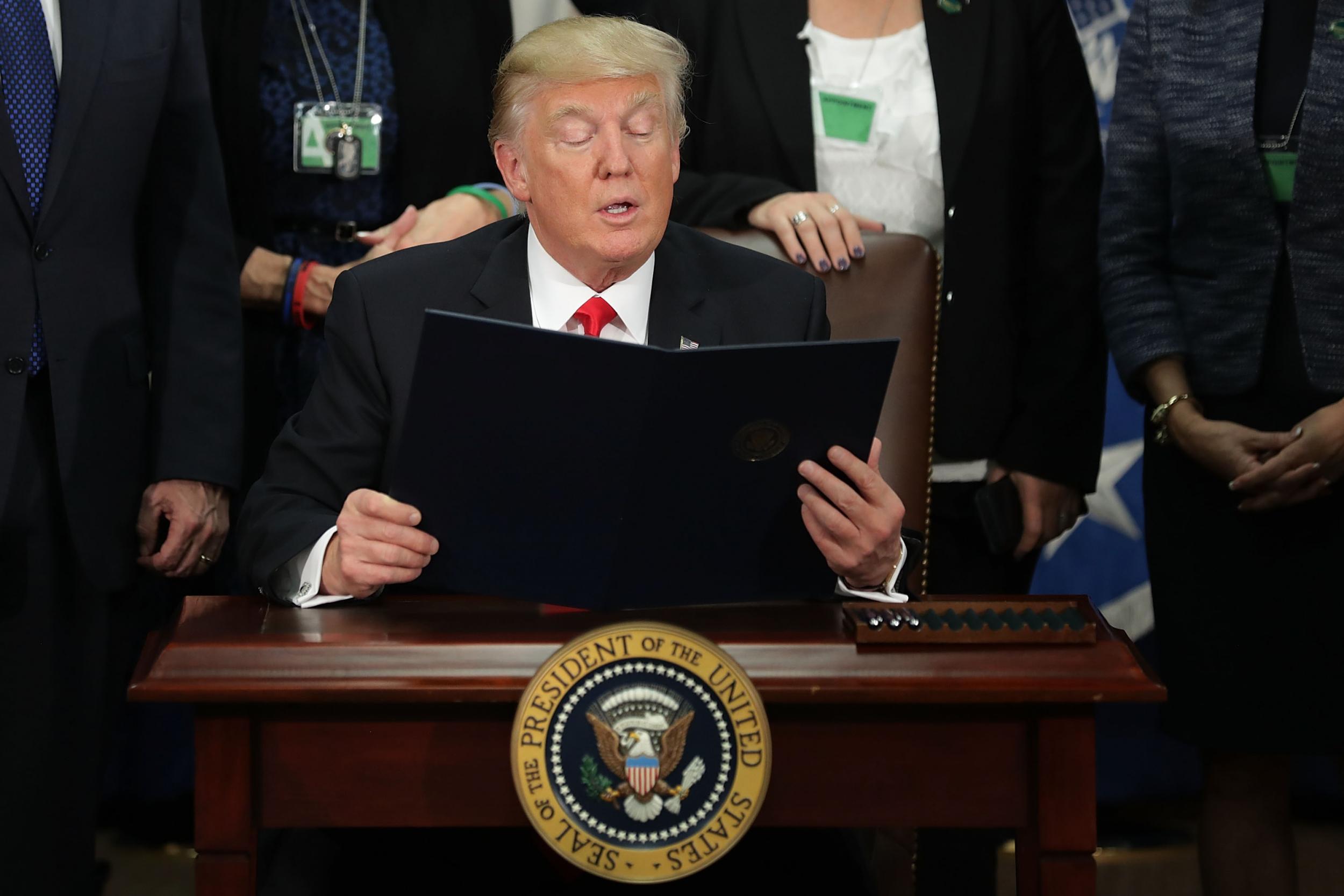 Mr Trump reading out an executive order halting the entry of refugees and people from seven majority Muslim countries