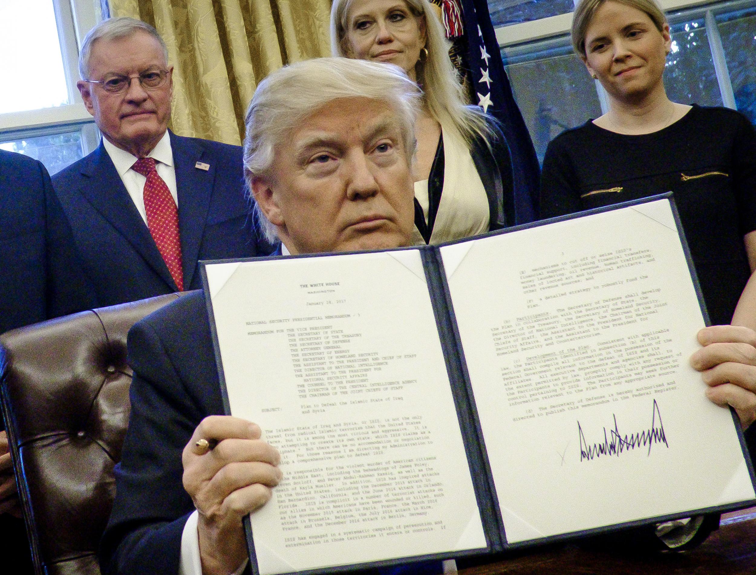 President Donald Trump holds up one of the executive actions that he signed in the Oval Office on January 28, 2017 in Washington, DC