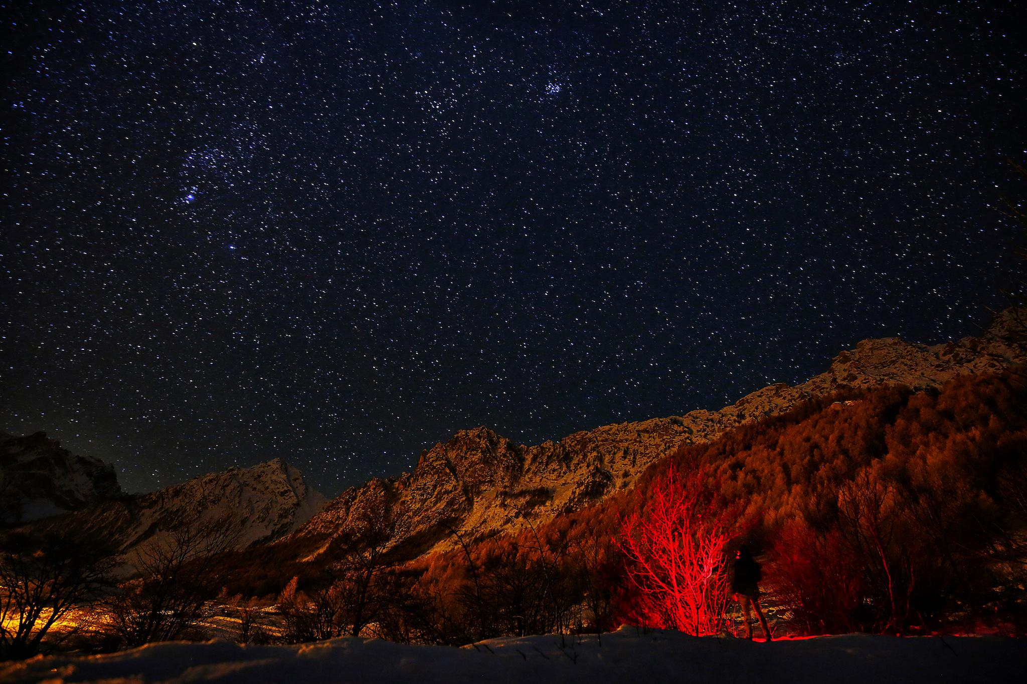 A photographer looks at the sky at night to see the annual Geminid meteor shower near Provenzales' rock, in Maira Valley, northern Italy on December 6, 2016