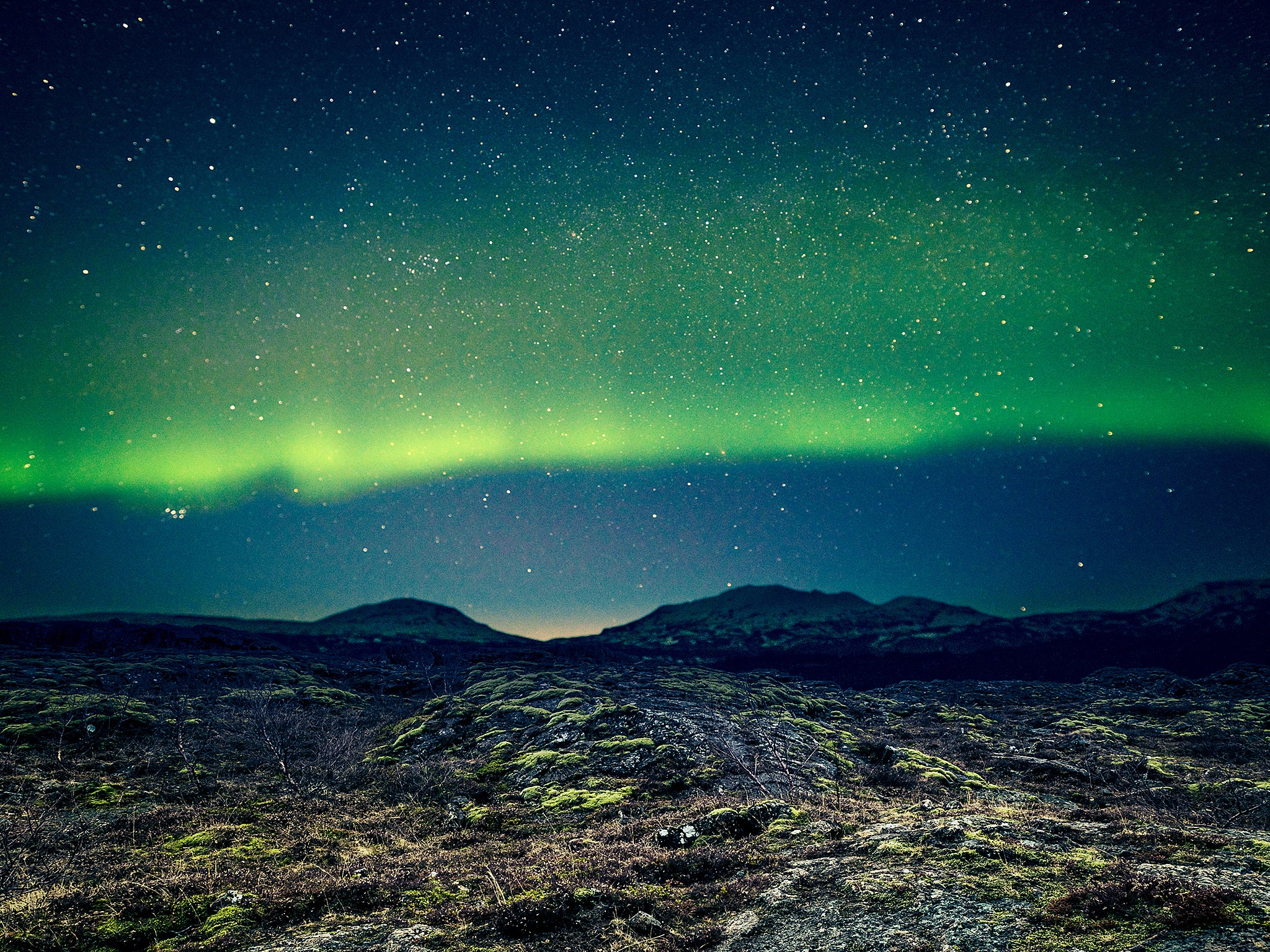 Aurora Borealis over distant mountains in Iceland (Getty)