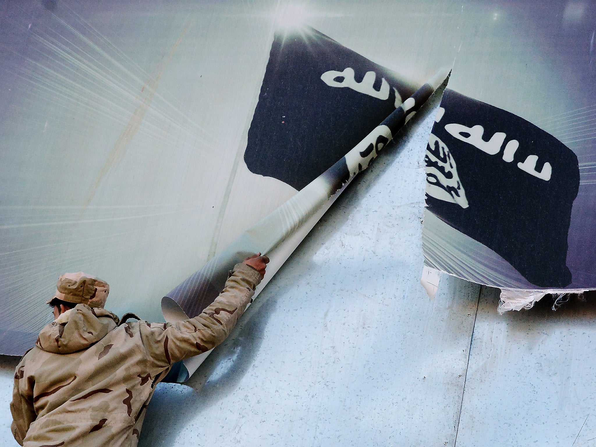 A member of the Iraqi security forces removes a banner bearing the logo of Isis in eastern Mosul last month