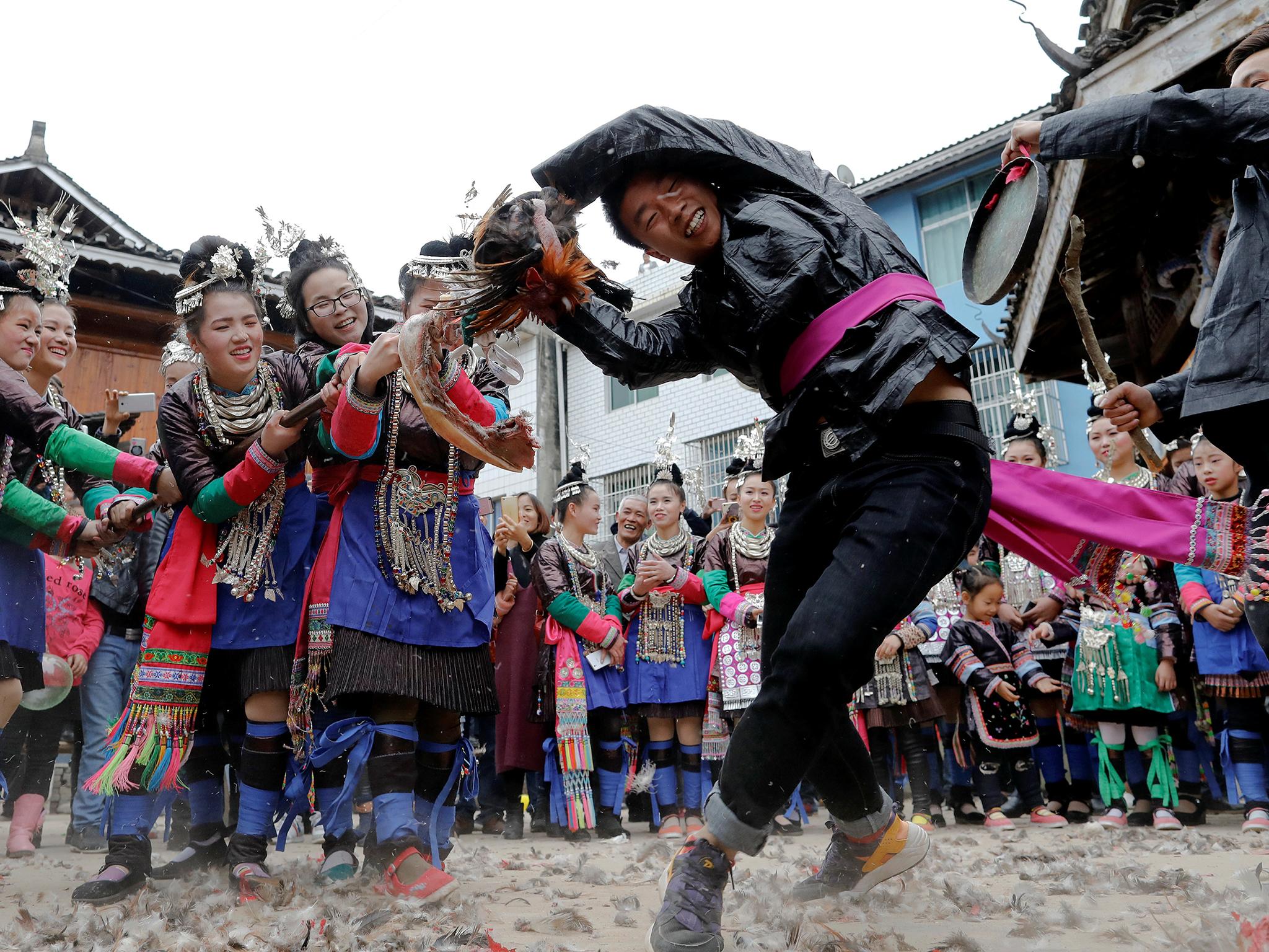 An ethnic 'Kam' (also known as Dong) man pulls a live chicken during a traditional wedding ritual known as the "steal the chicken at the drum tower"