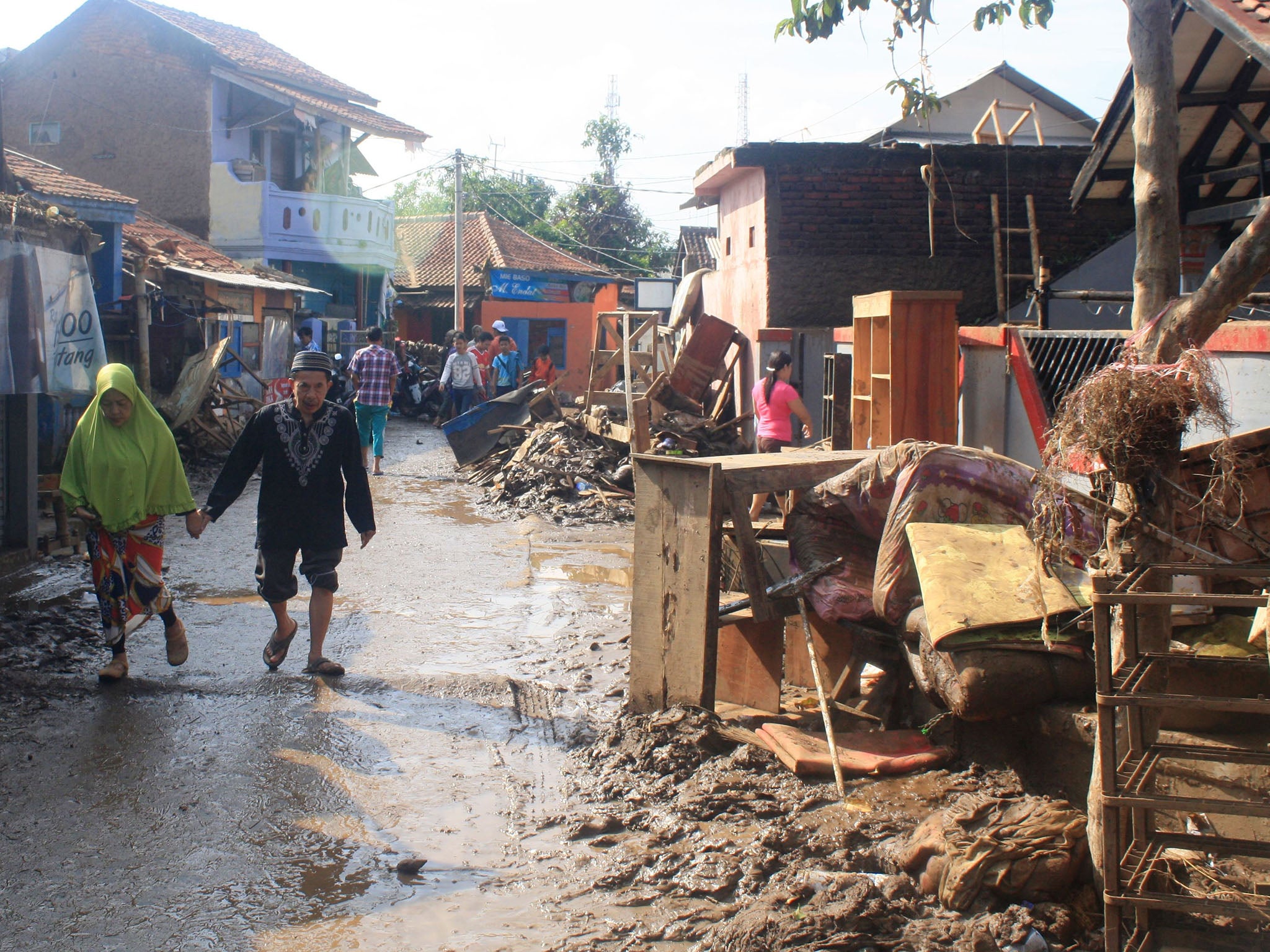 An elderly couple walk past debris on the Cimanuk river banks in Garut district, West Java province on September 22, 2016 following floods