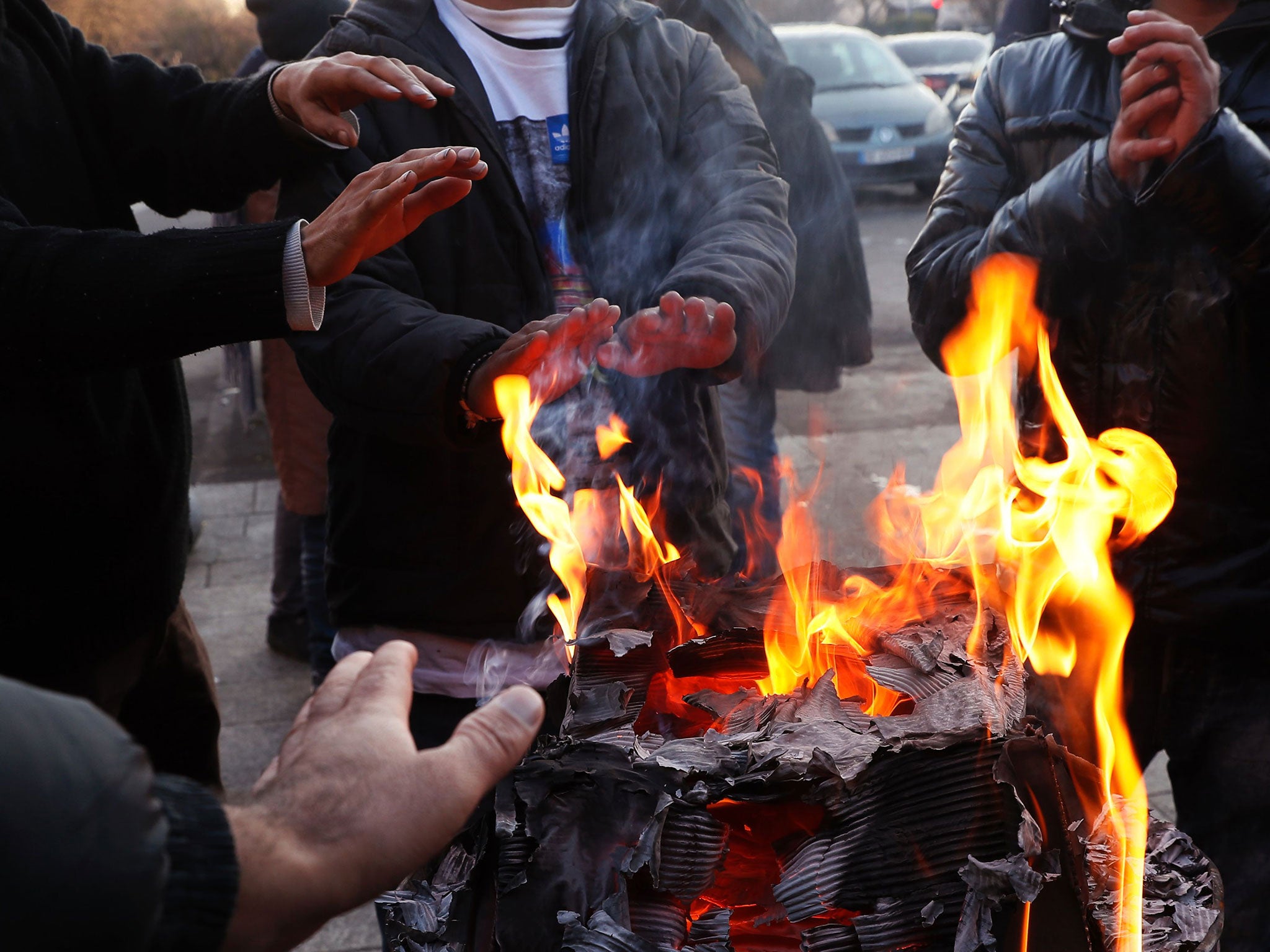 &#13;
Men around a bonfire at the makeshift refugee camp set up near Porte de la Chapelle, Paris, on 8 December (AFP/Getty)&#13;