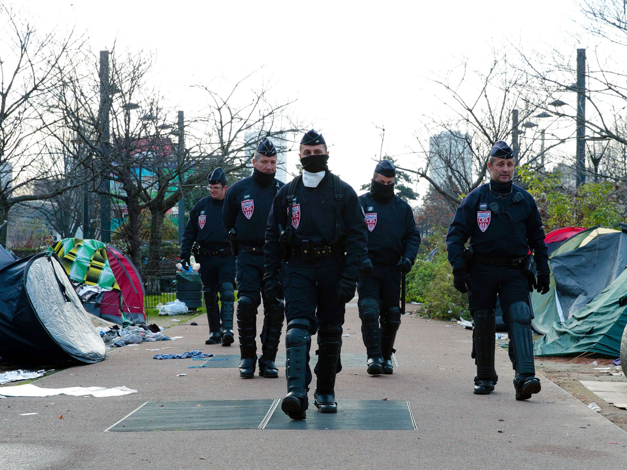 &#13;
Police dismantling a makeshift camp set up by migrants in Saint-Denis, Paris, on 16 December (AFP/Getty)&#13;