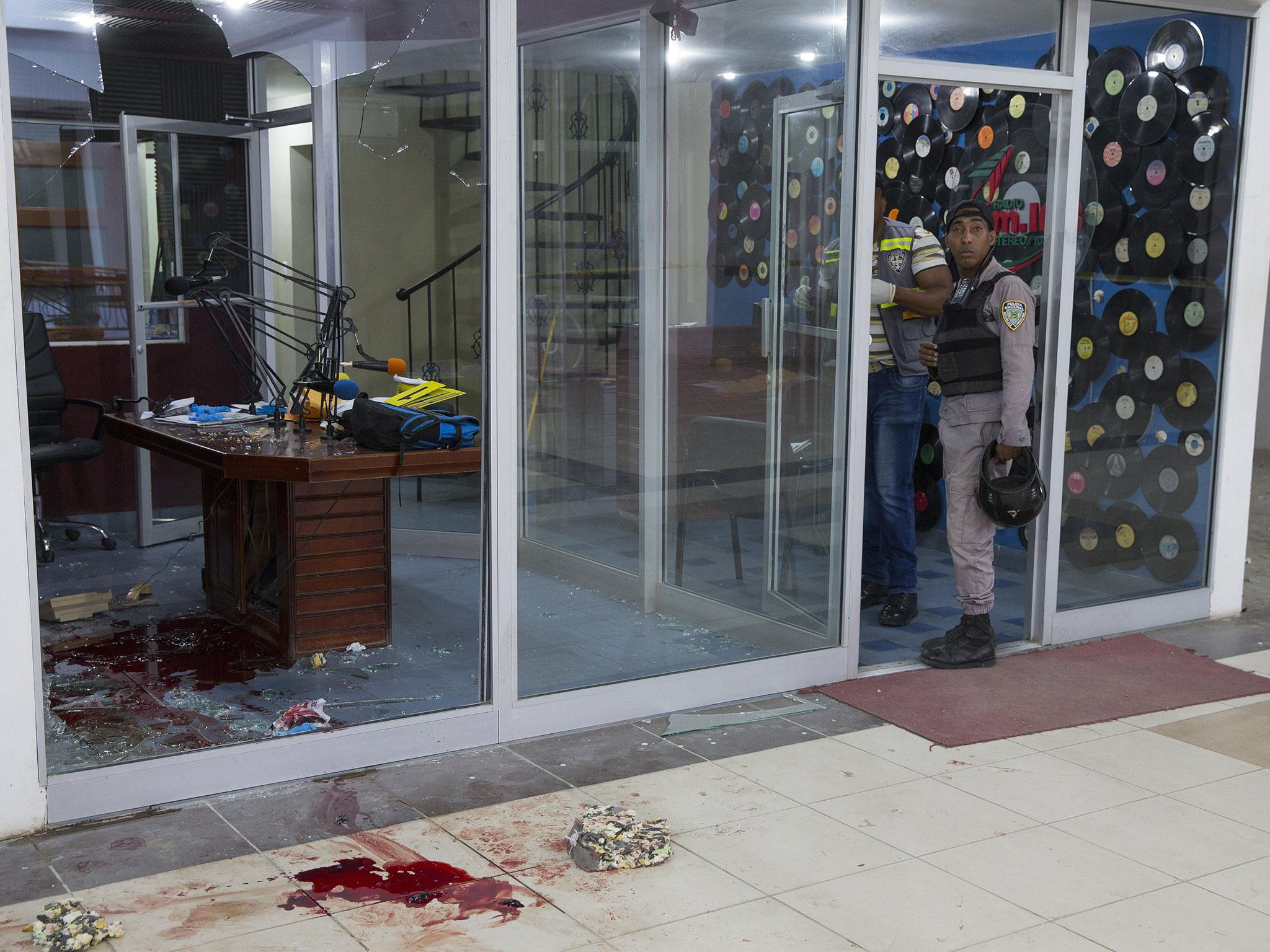 Members of the Dominican police investigate the facilities of the 103.5 radio station following the murder of the two journalists