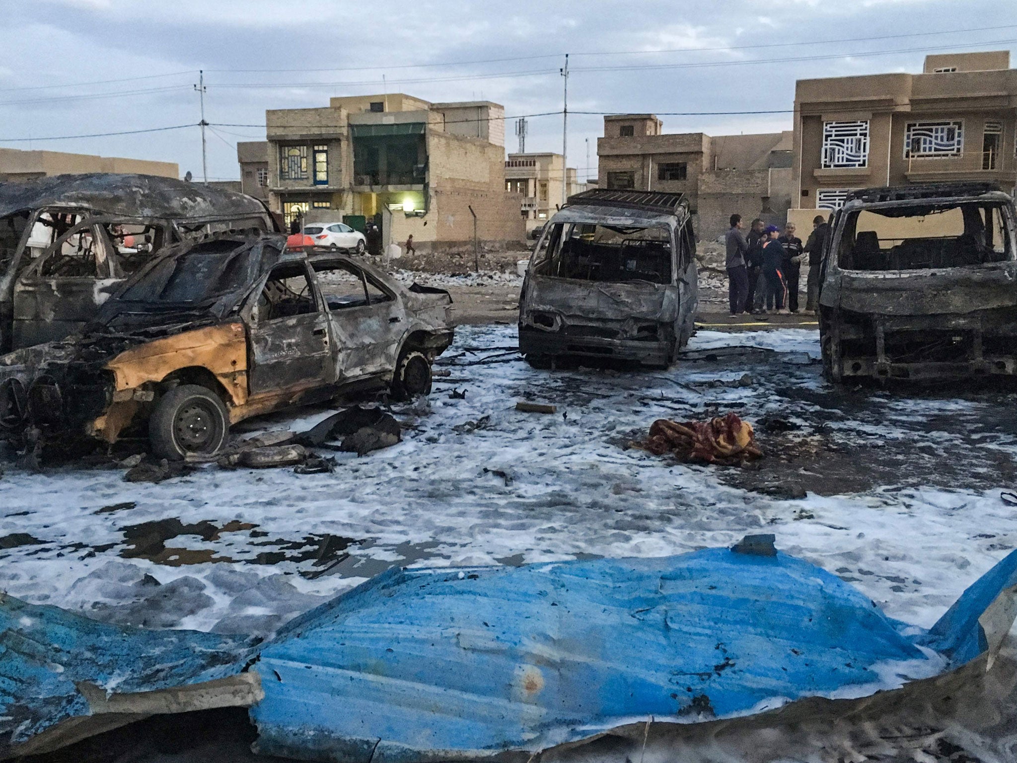 Men look at the wreckage of a burnt car after a suicide bomber detonated a pick-up truck on Wednesday in Sadr City, a heavily populated poor Shi'ite suburb of Baghdad, Iraq, February 16, 2017