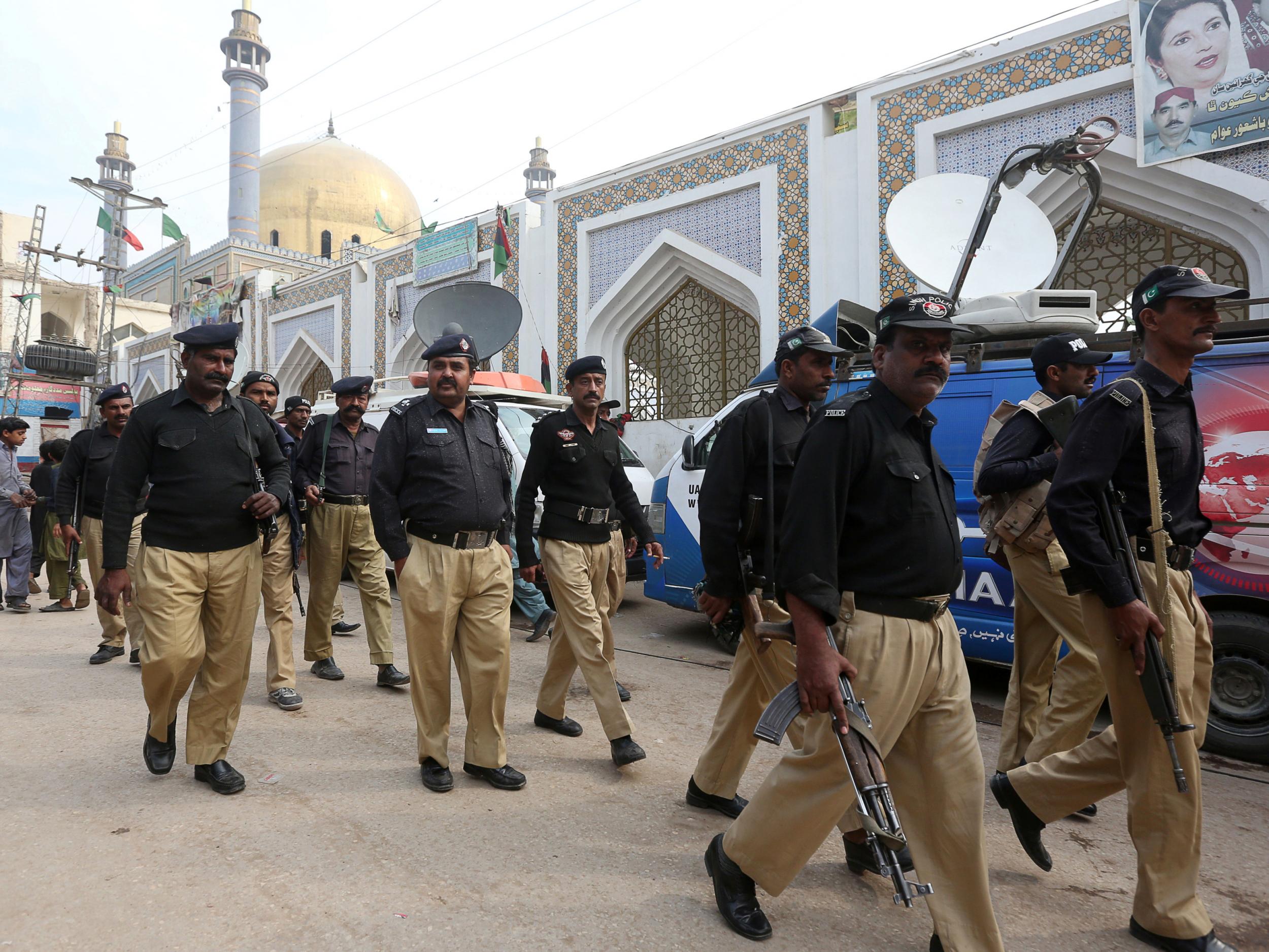 Policemen gather outside the tomb of Sufi saint Syed Usman Marwandi, also known as the Lal Shahbaz Qalandar shrine, after Thursday’s suicide blast in Sehwan