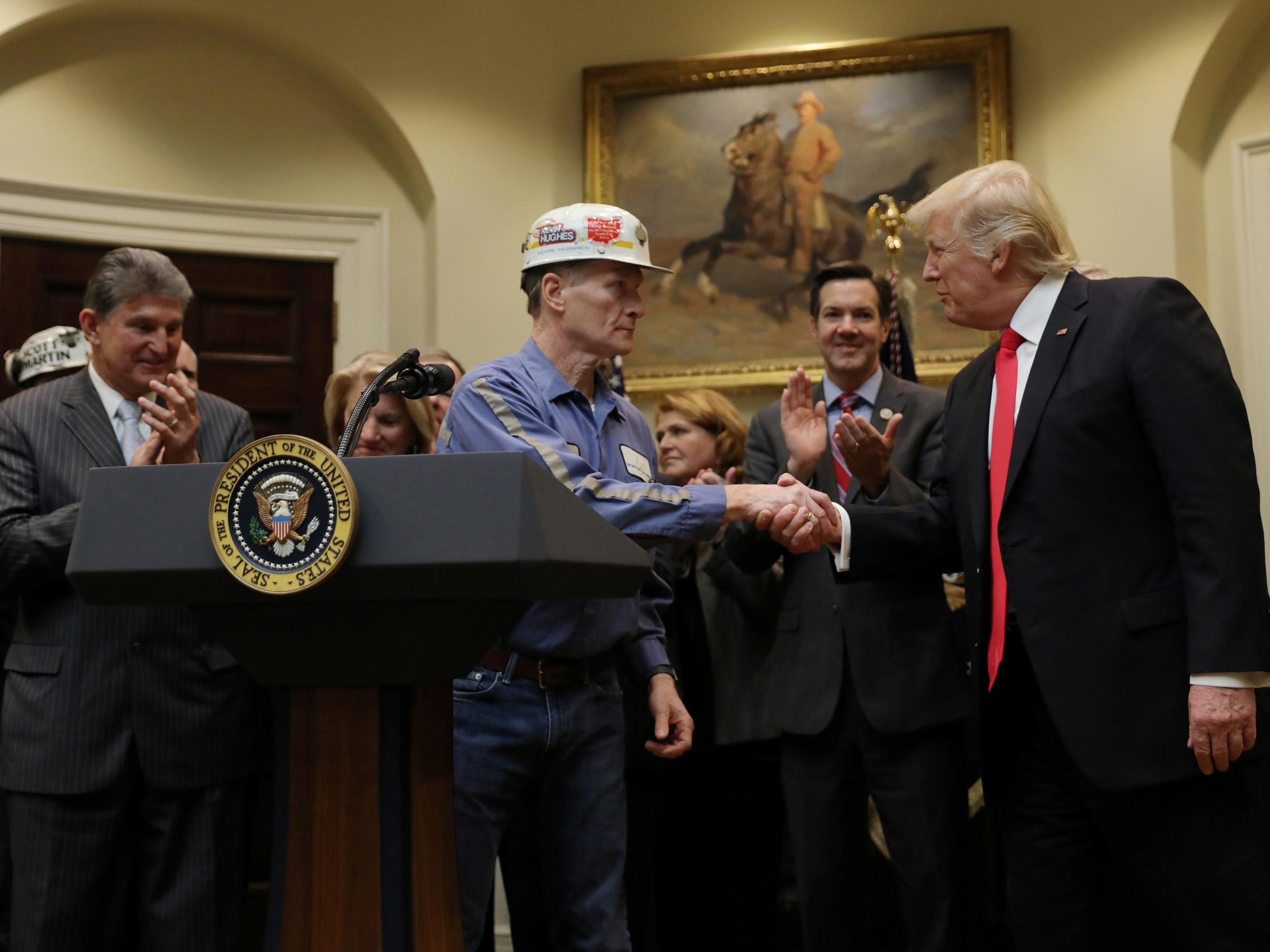 A coal miner shakes hands with US President Donald Trump as he prepares to sign Resolution 38