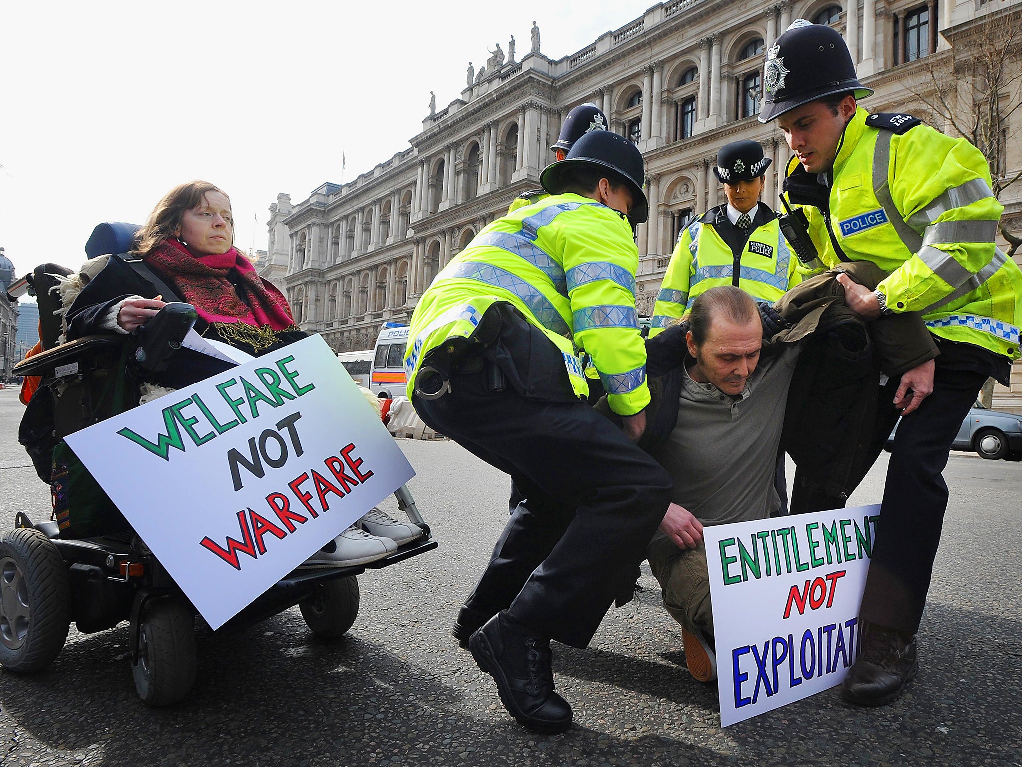 Police remove disabled protesters to the side of the road Whitehall, London where they were demonstrating about Government welfare policy and provision