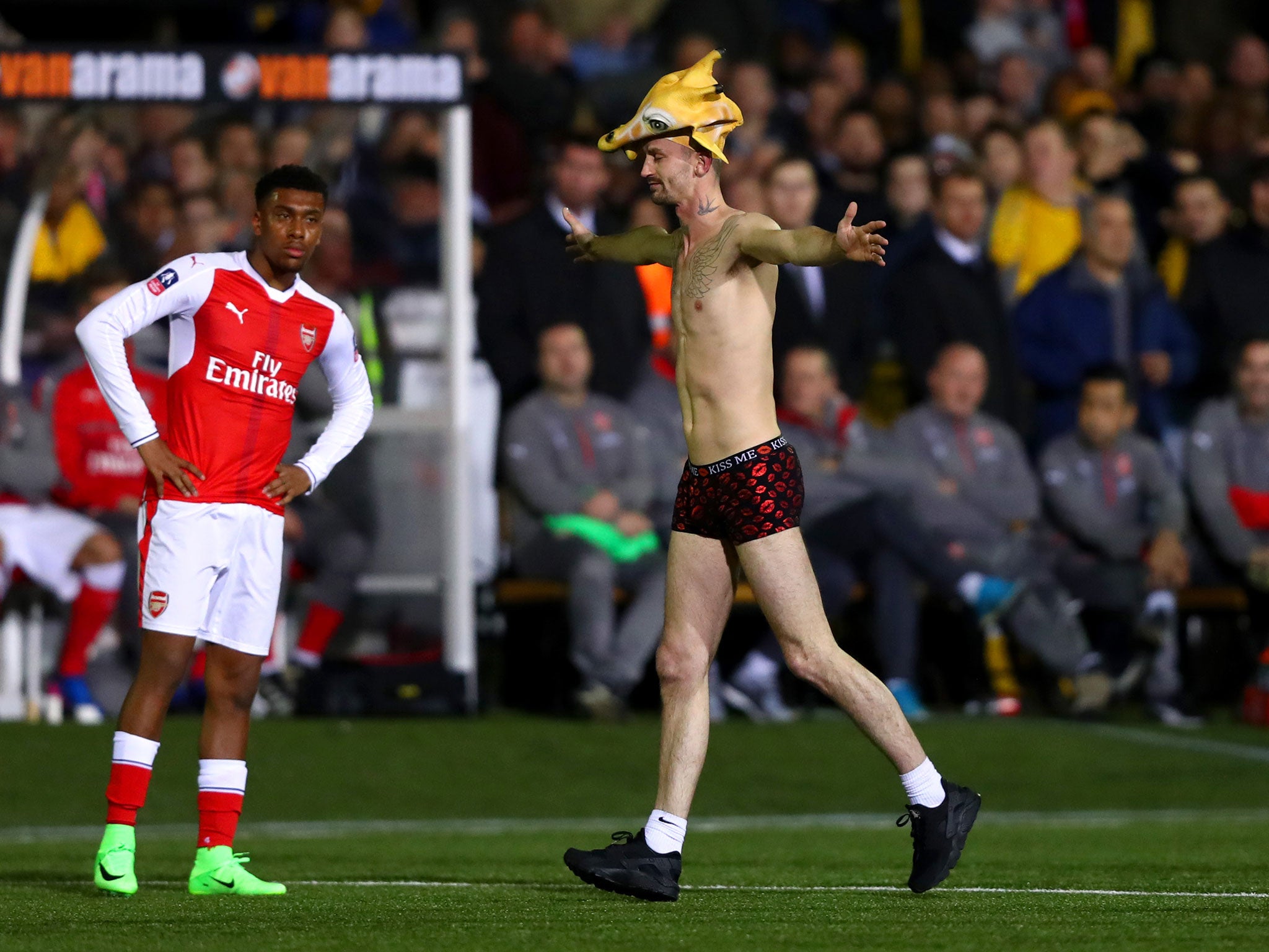 The pitch invader jogs past an unimpressed Alex Iwobi