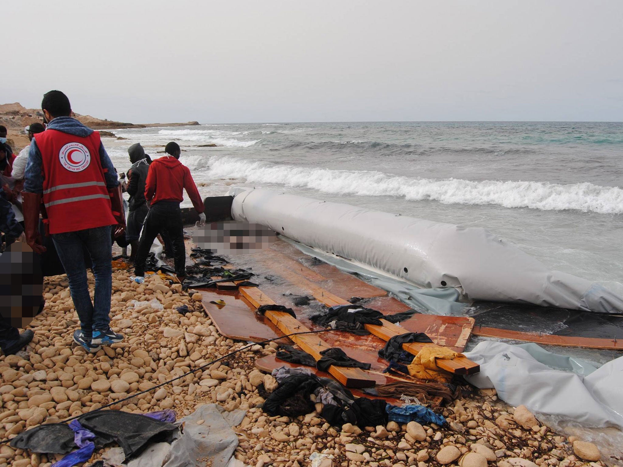 Bodies (blurred) on a beach and inside a wrecked migrant dinghy on a beach near the Libyan port of Zuwiyah on 20 February 2017