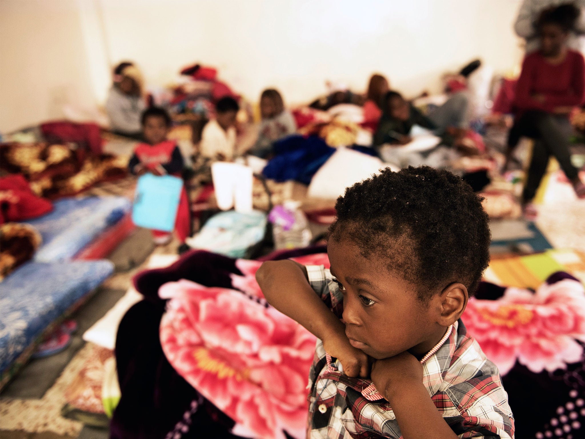 A child stands in a room where women and children sleep on old mattresses laid on the floor at a detention centre, in Libya