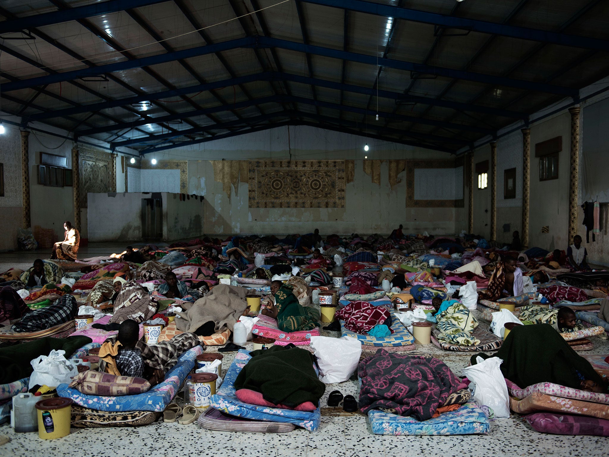 Migrants lie on mattresses inside a detention centre in Libya. At one time, up to 720 people were being held at the centre, which was once used as a dining hall for weddings