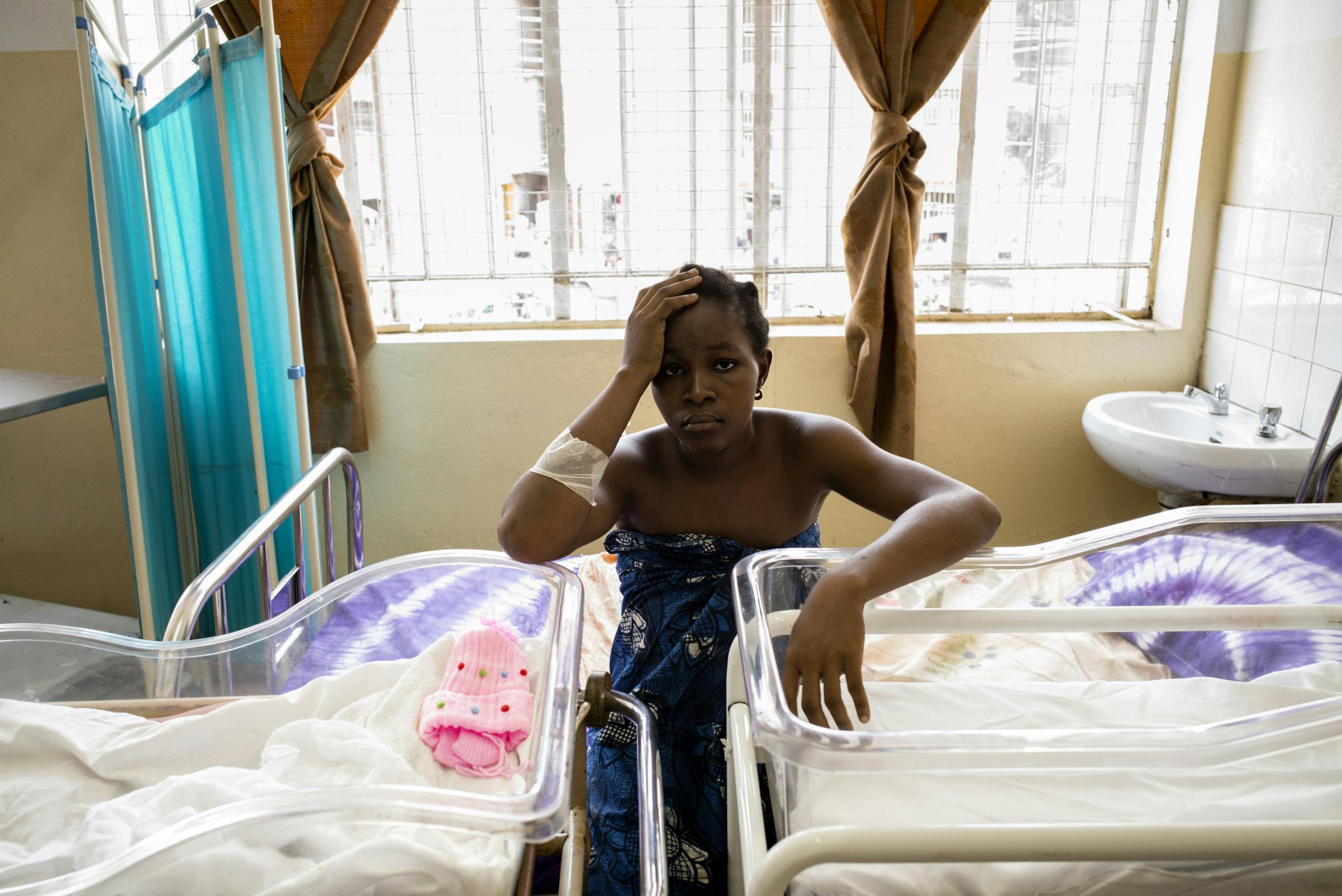 A young mother of twins waits for her children to receive vaccinations in Freetown, Sierra Leone, which has the highest maternal mortality rate in the world