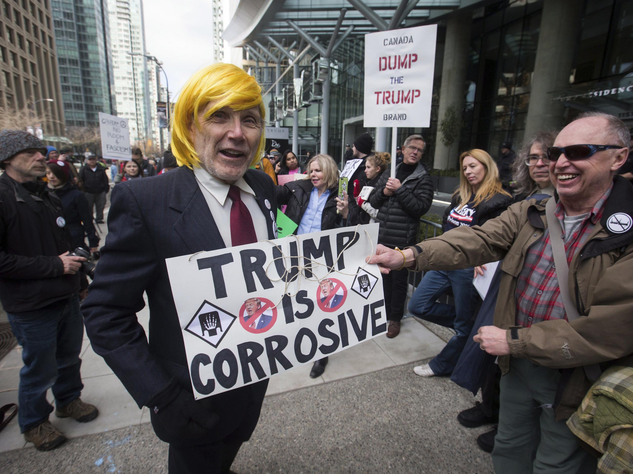 A man dressed as US President Donald Trump jokes with protesters outside the official opening of the Trump International Hotel and Tower in Vancouver