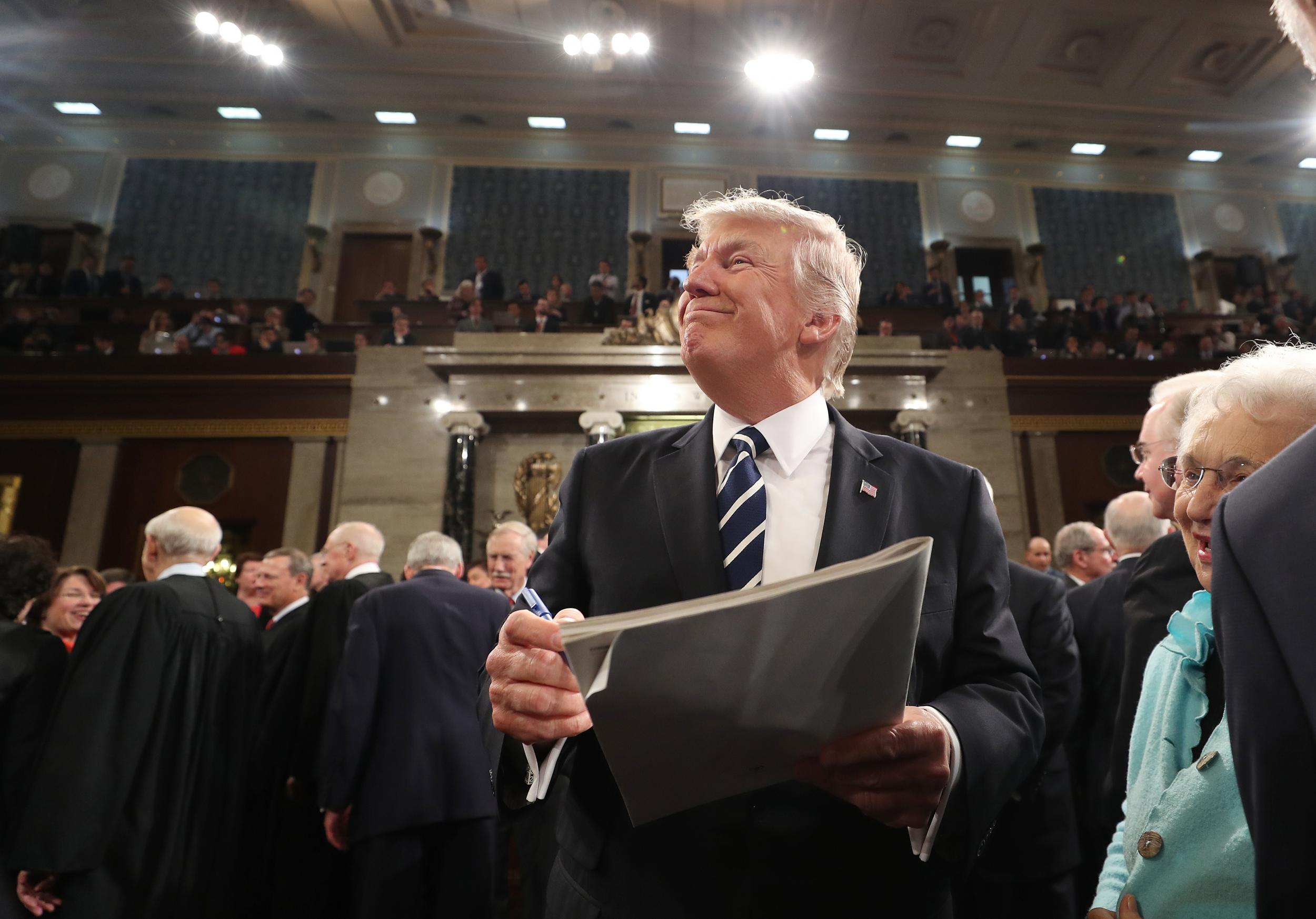 US President Donald Trump signs an autograph on his way out after delivering his first address to a joint session of Congress