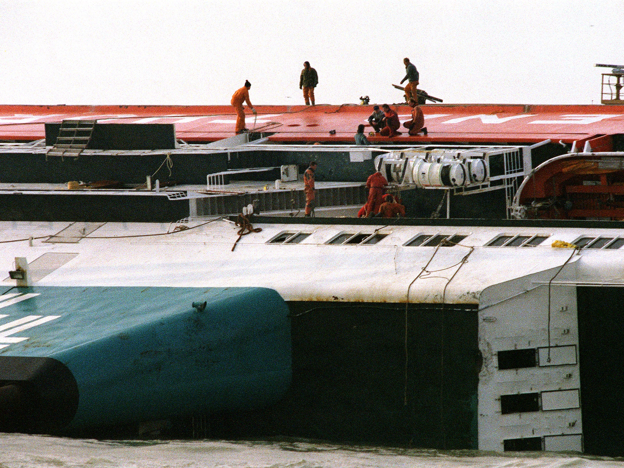 Rescuers on the hull of the ferry, which capsized in just two minutes (Getty)