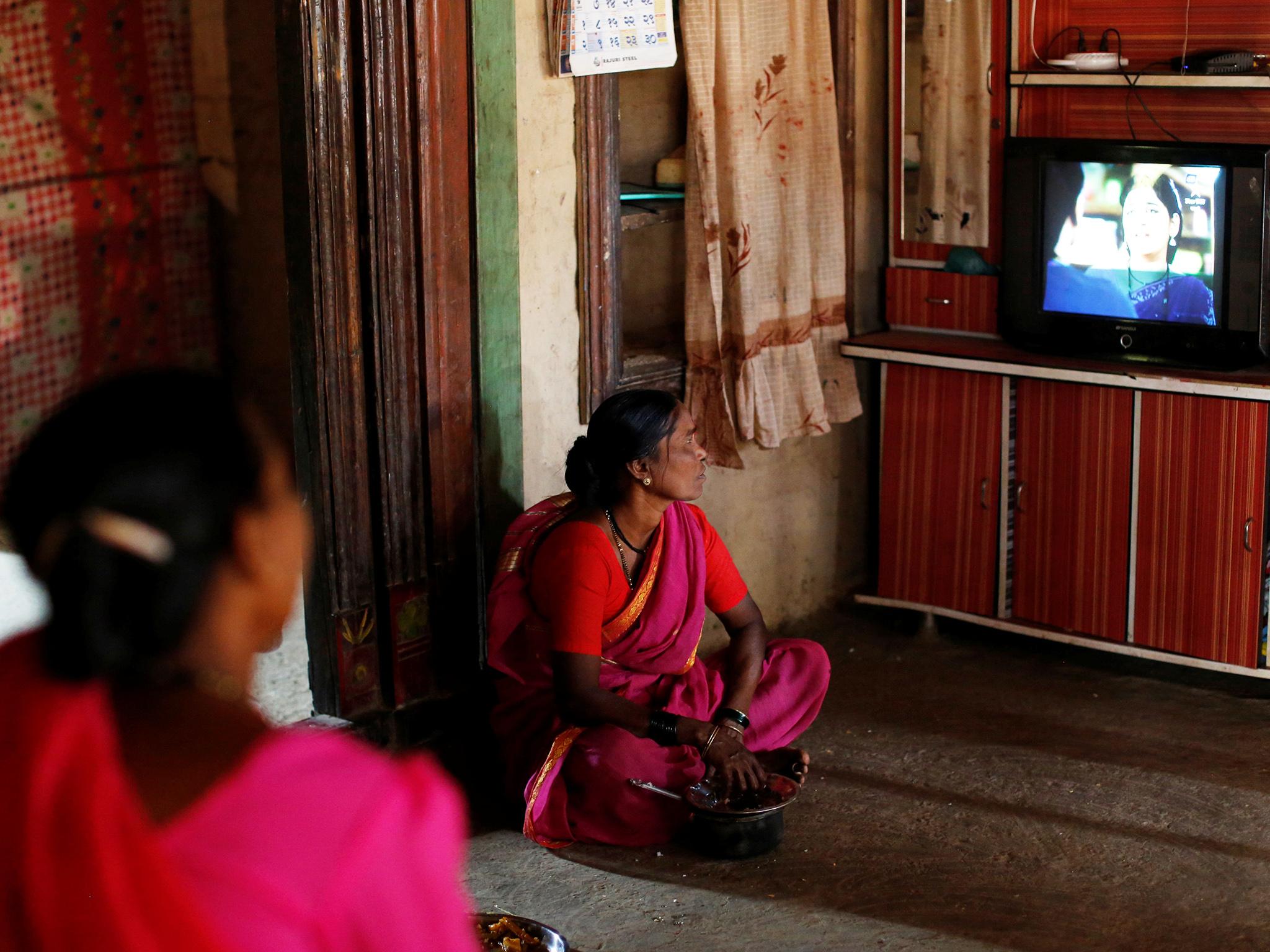 Indu Pawar, 61, who studies at Aajibaichi Shaala (Grandmothers' School), watches television inside her house in Fangane village, India