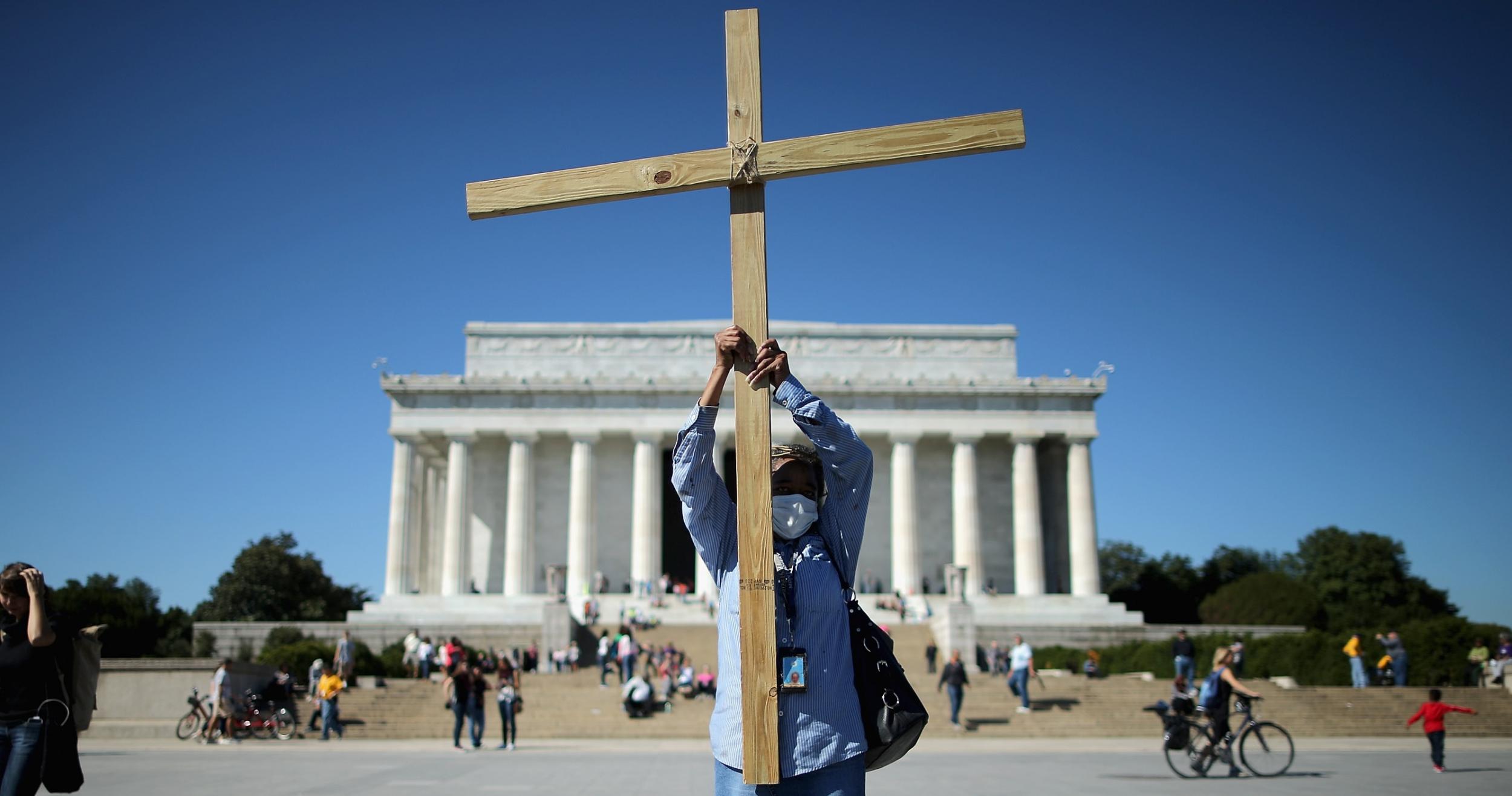 A woman raises a wooden cross during a prayer gathering in Washington DC