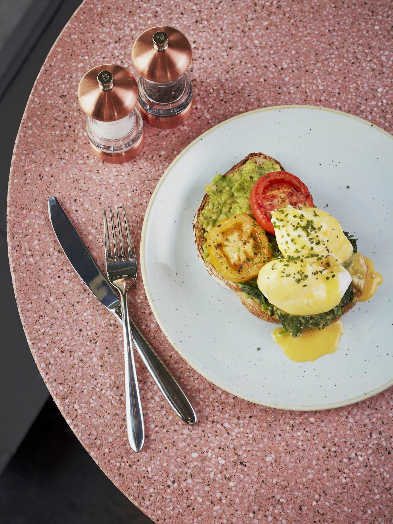 Smashed avocado and poached eggs with tomatoes and spinach