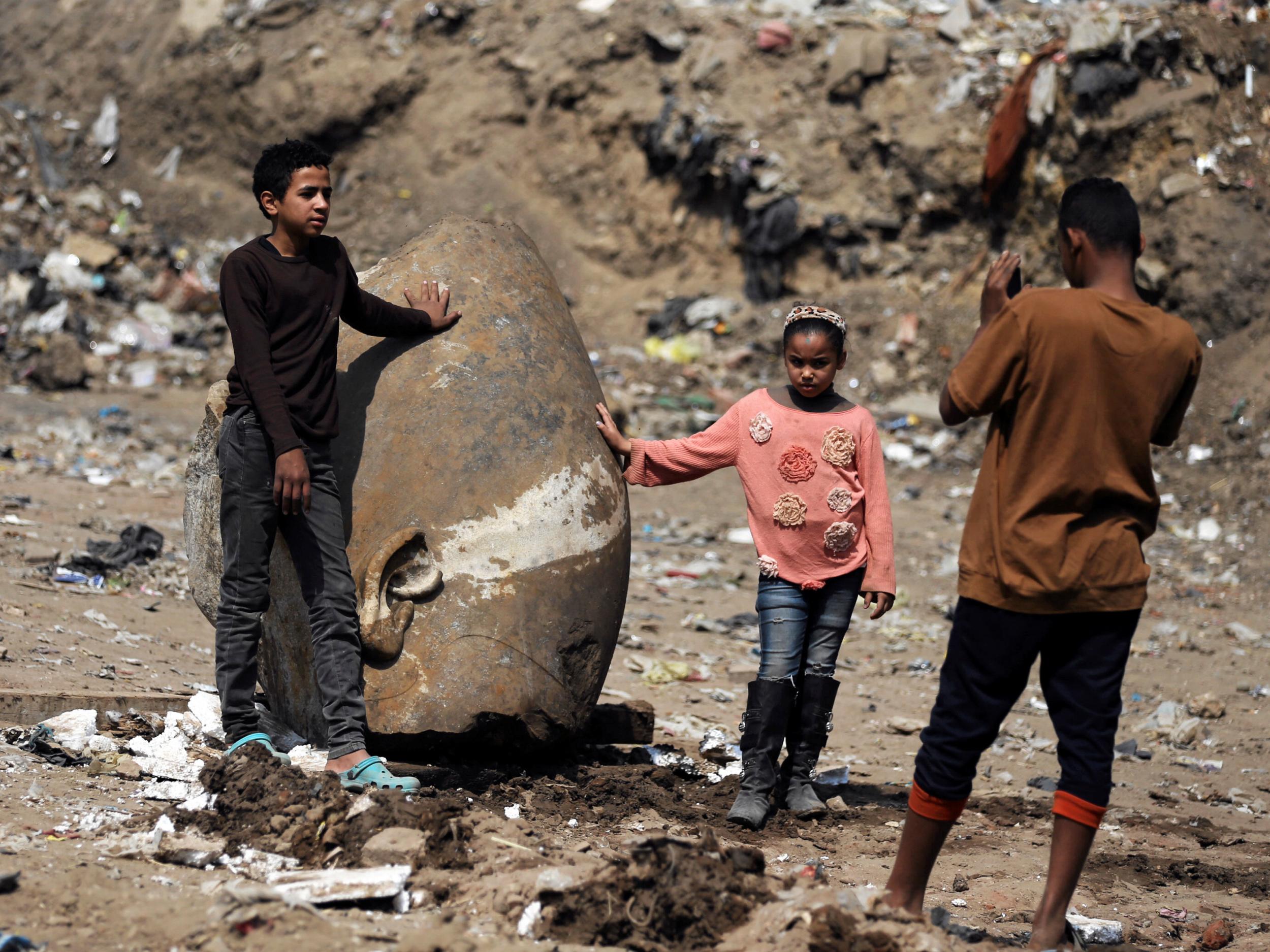 Matariya residents pose for pictures with what appears to be the head of an unearthed statue of Pharaoh Ramses II