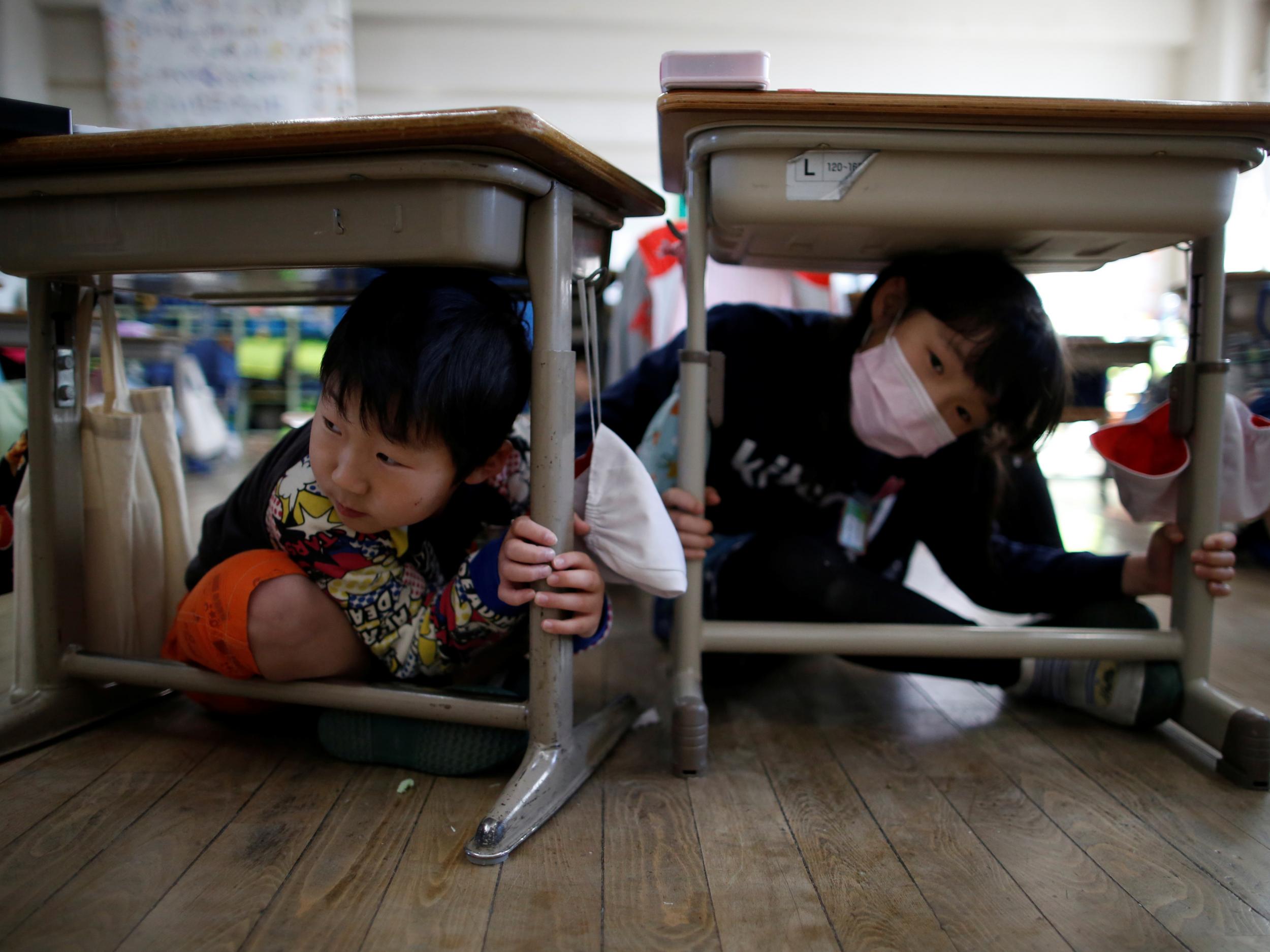 Pupils take shelter under desks as part of quake drills ahead of the six-year anniversary of the Fukushima nuclear disaster