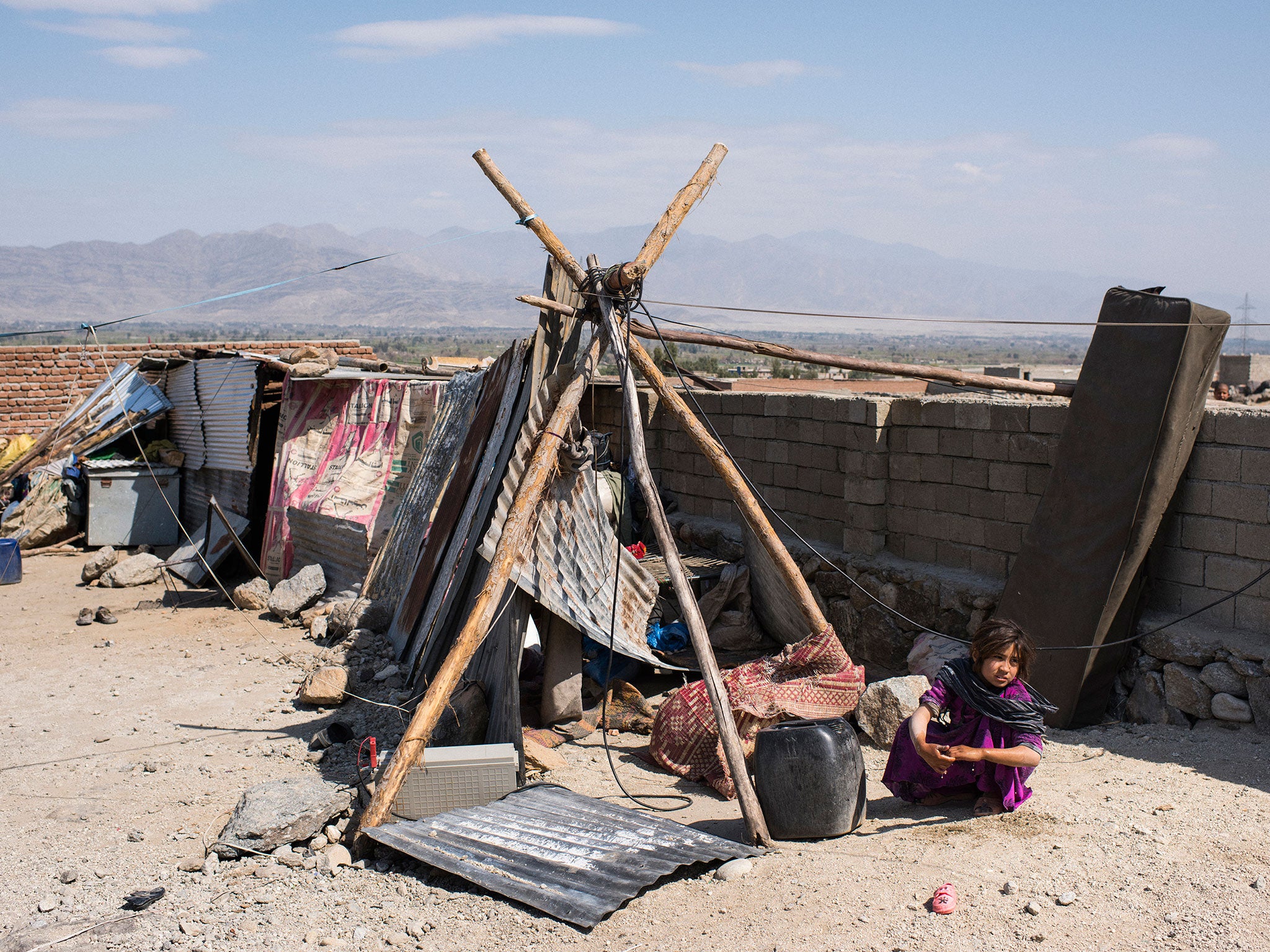 &#13;
A young girl washes her hands as she squats beside her family’s shelter. The nearest drinking water is several miles away &#13;