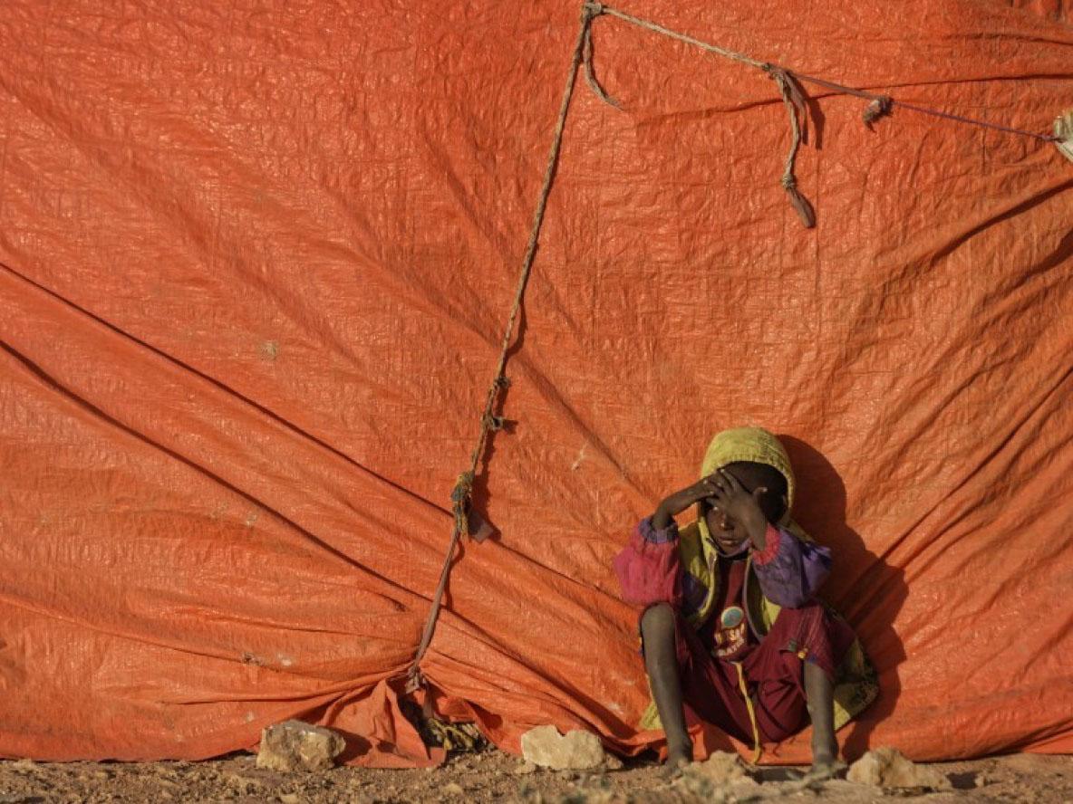 A Somali boy sits outside his makeshift hut at a camp for people displaced from their homes by drought