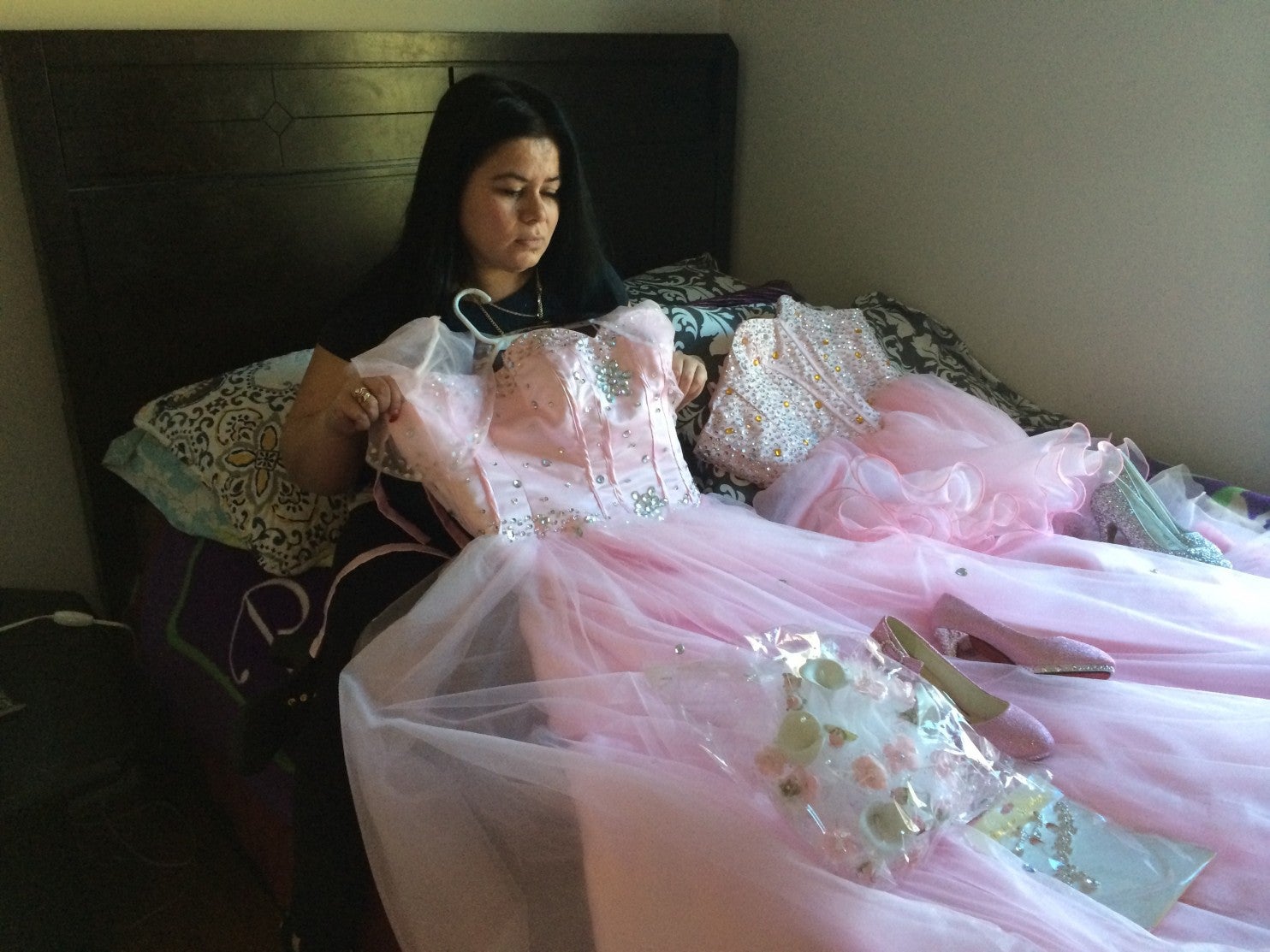 Maria holds the dress her daughter Damaris picked for her quinceañera [15th birthday celebration]