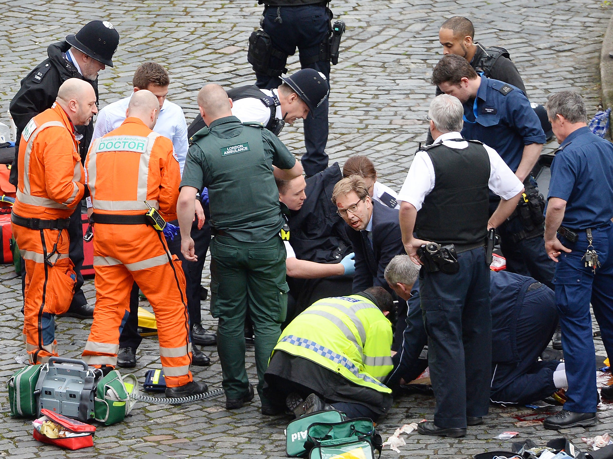 Conservative MP Tobias Ellwood (centre) helps emergency services attend to a police officer outside the Palace of Westminster, London, after a policeman was stabbed