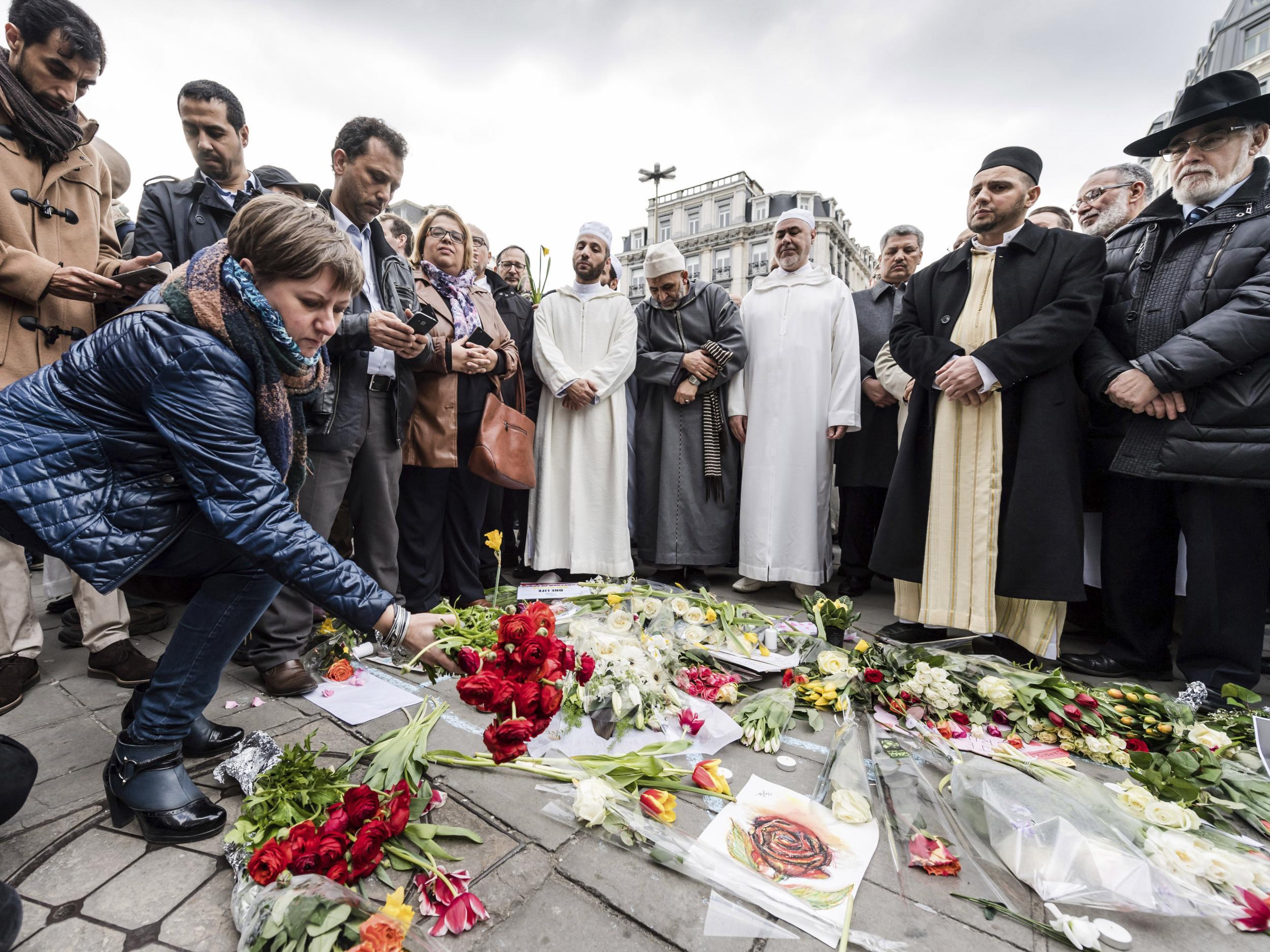 A woman lays flowers on a makeshift memorial at the Bourse