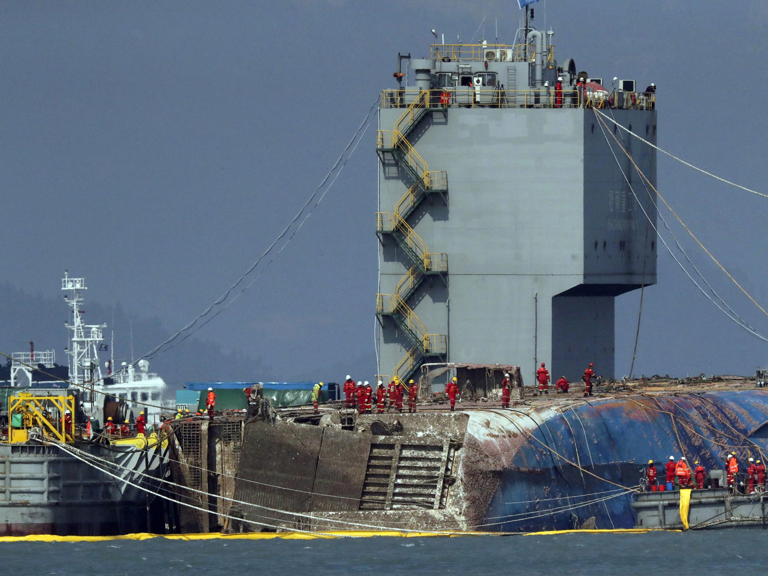 Workers try to raise the sunken Sewol ferry between two barges during the salvage operation in waters off Jindo, South Korea