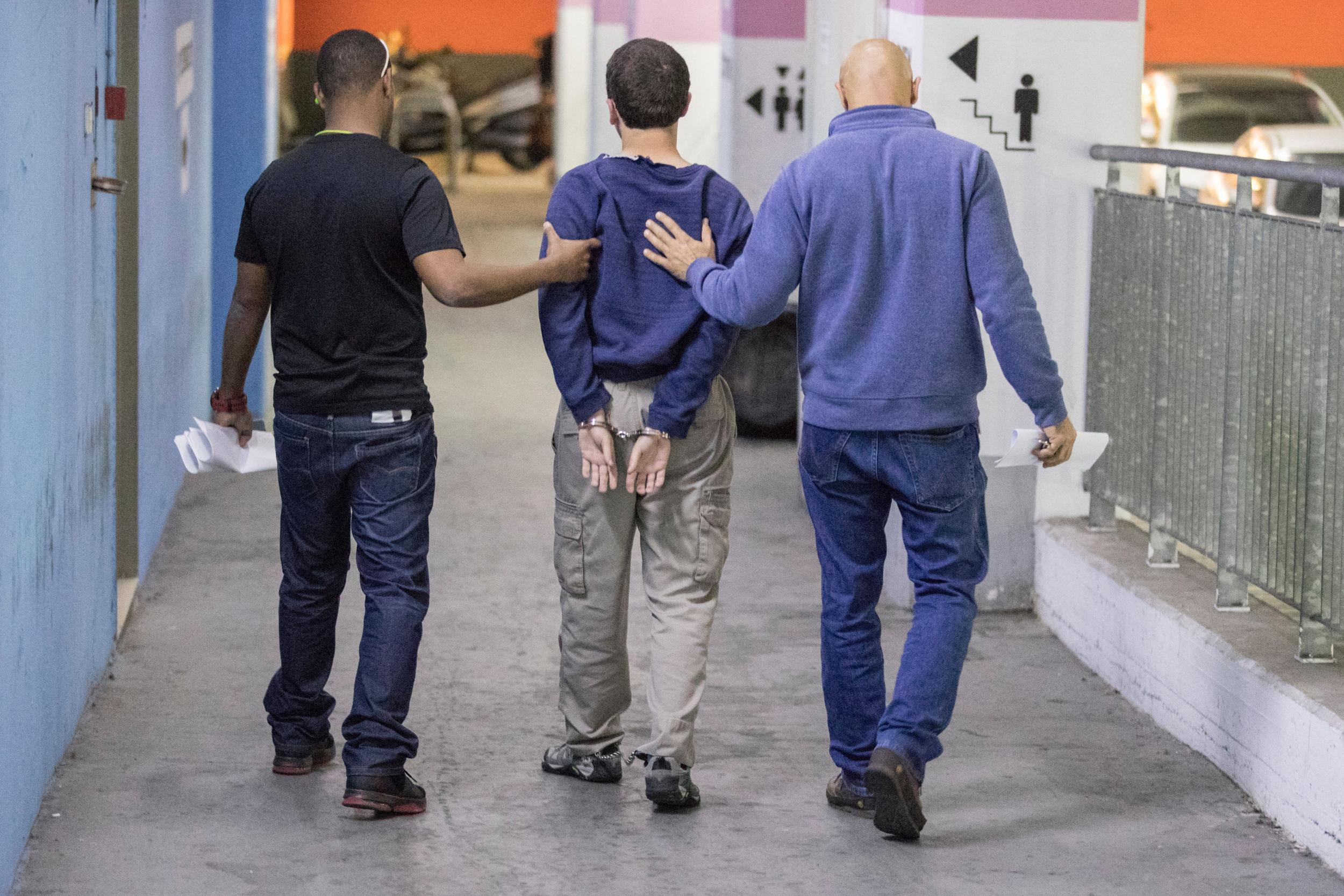 The suspect is escorted by guards as he leaves the Israeli Justice court