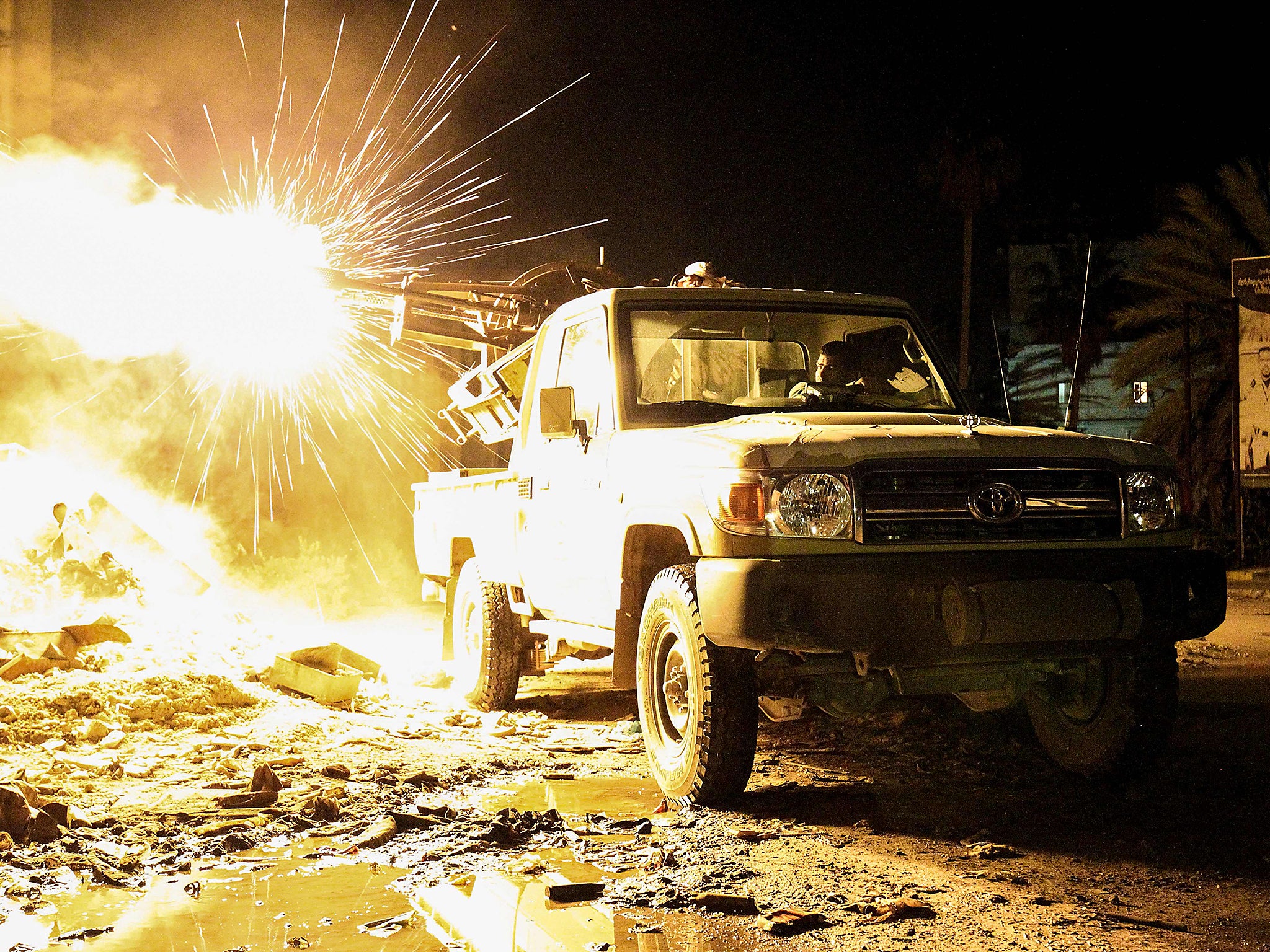 A member of the Libyan National Army (LNA) fires a machine gun mounted on the back of a Toyota pickup truck against jihadists in district of Suq al-Hut in the eastern coastal city of Benghazi