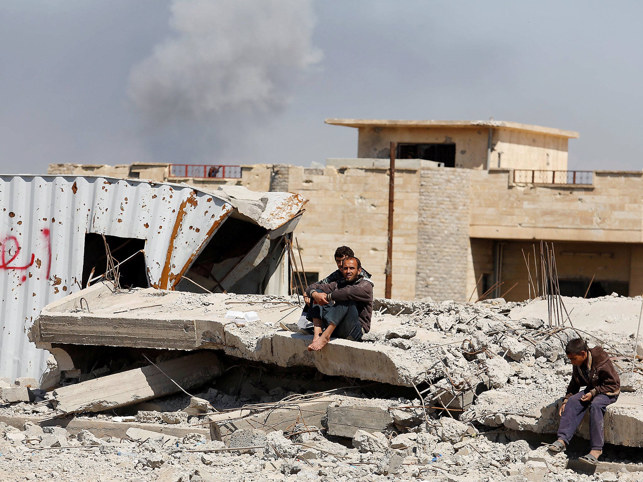 moke rises while displaced Iraqis wait to get food supplies as Iraqi forces battle with Islamic State militants, in western Mosul, Iraq