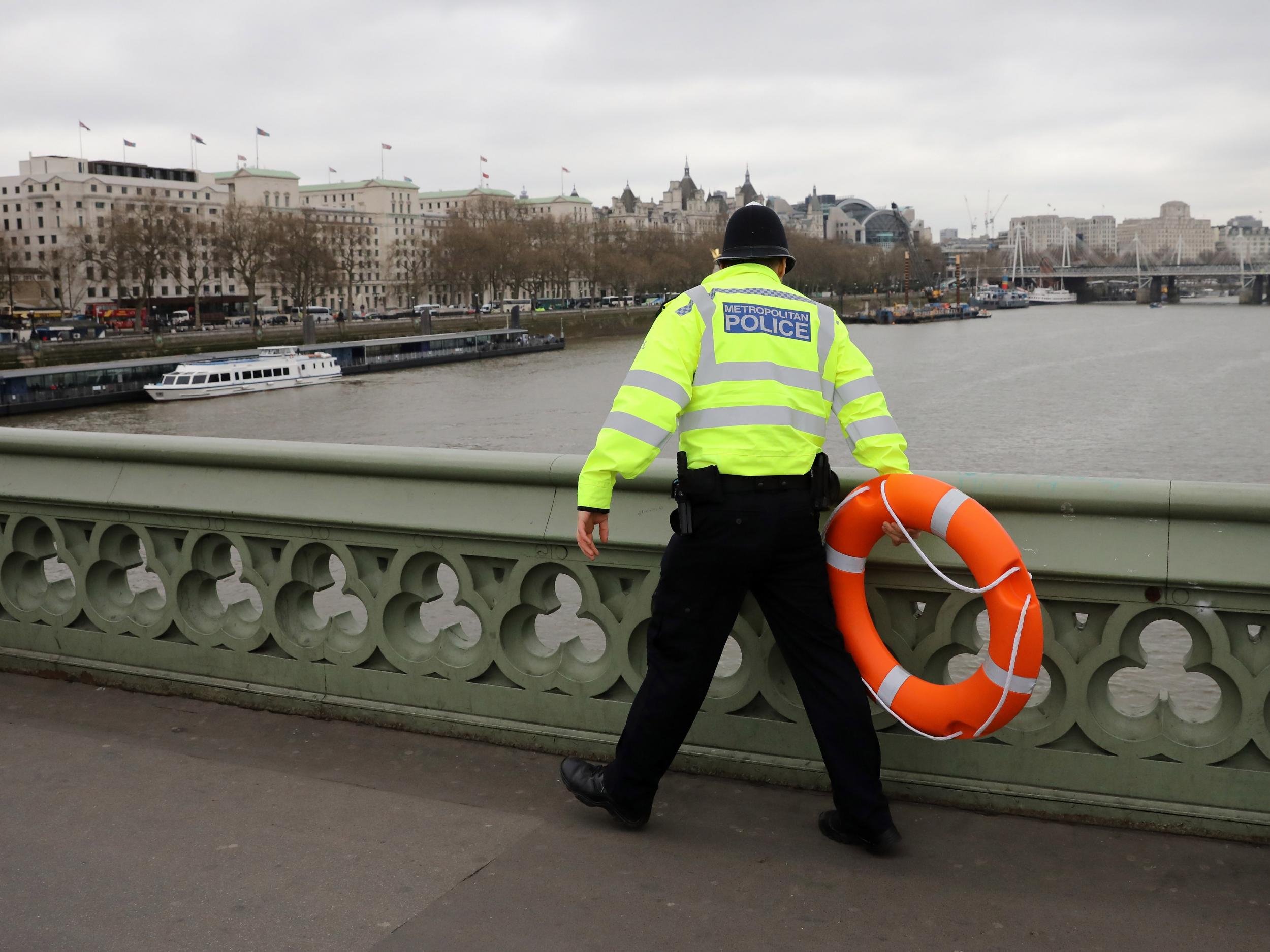 Police officer looks for a person thought to have fallen from Westminster Bridge